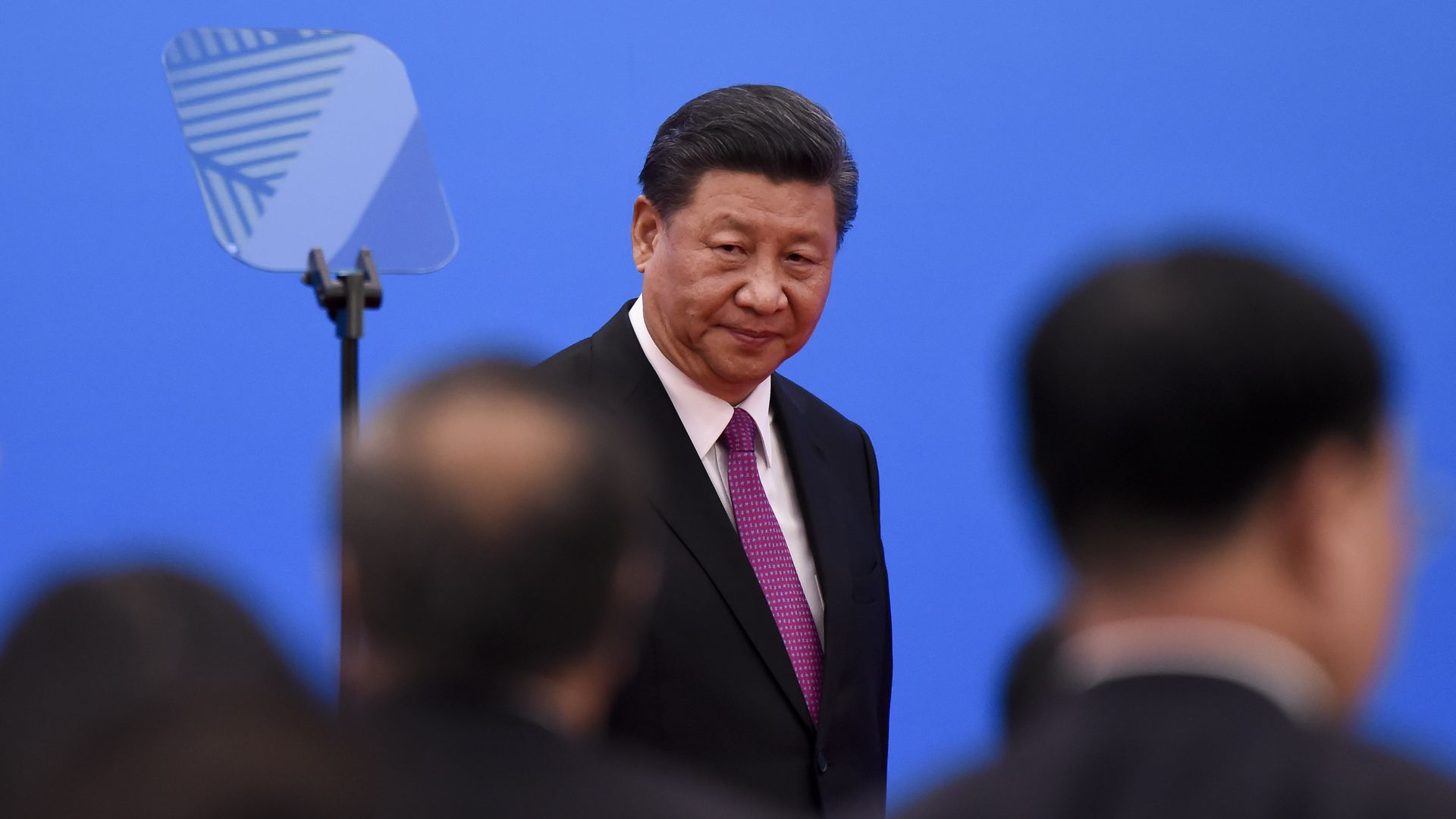 In this image, Xi Jinping looks to the left while walking on a stage.