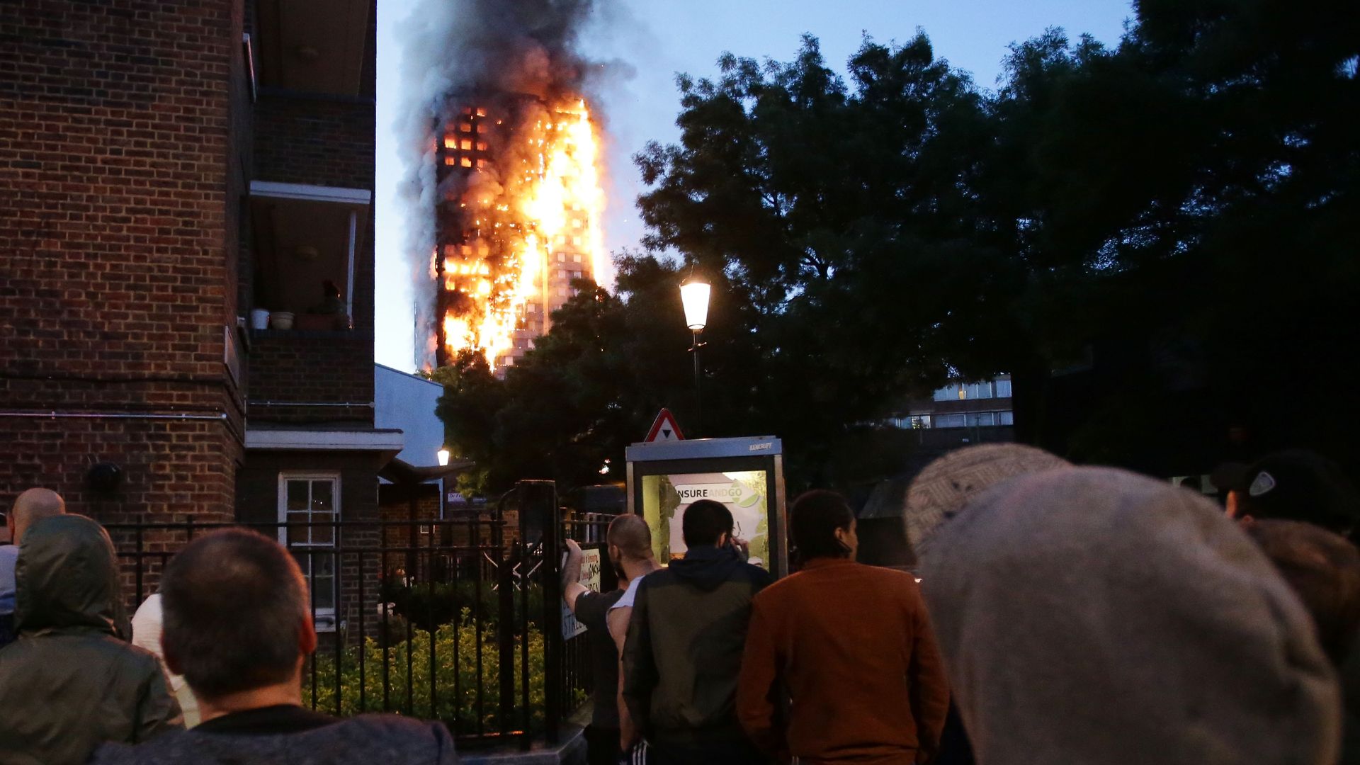 Local residents watch as Grenfell Tower is engulfed by fire on June 14, 2017 in west London.