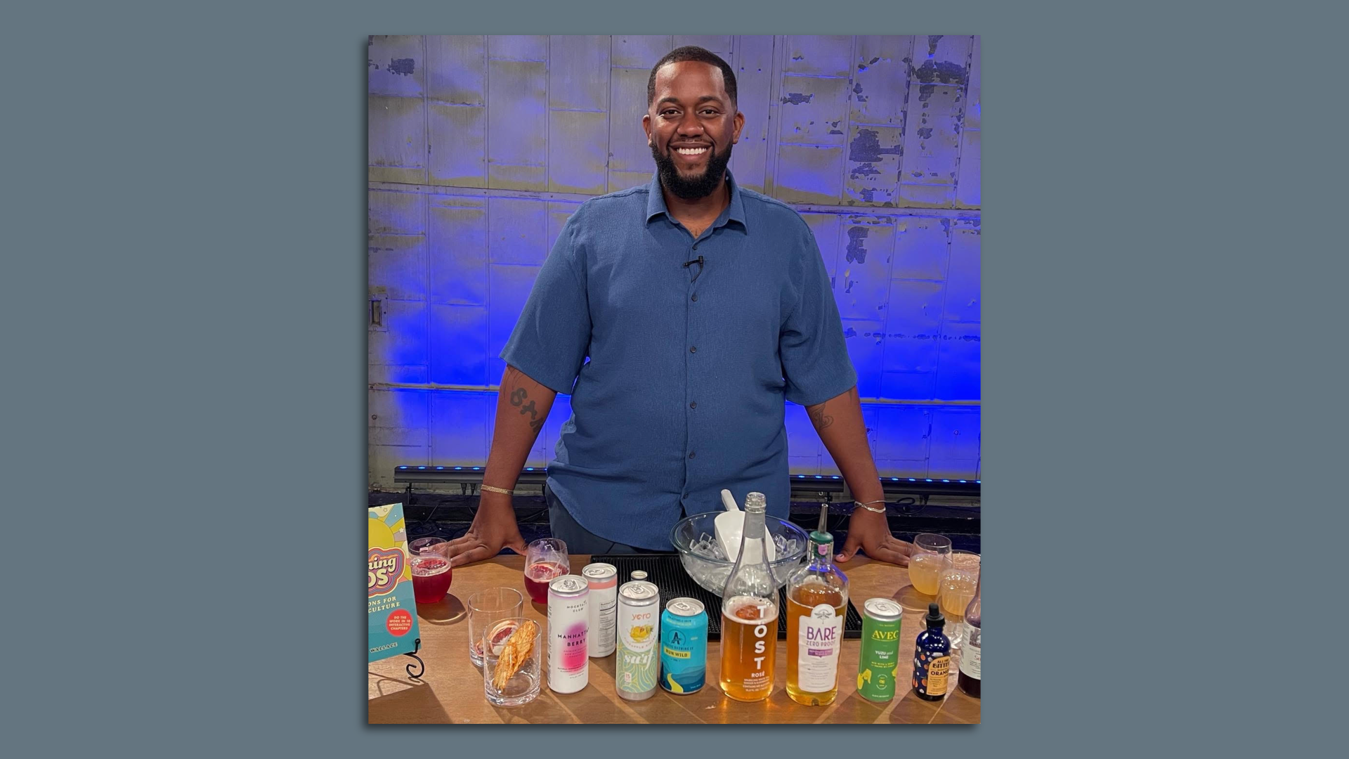 Photo shows David Wallace standing behind a table with multiple bottles, cans and other drinks displayed.
