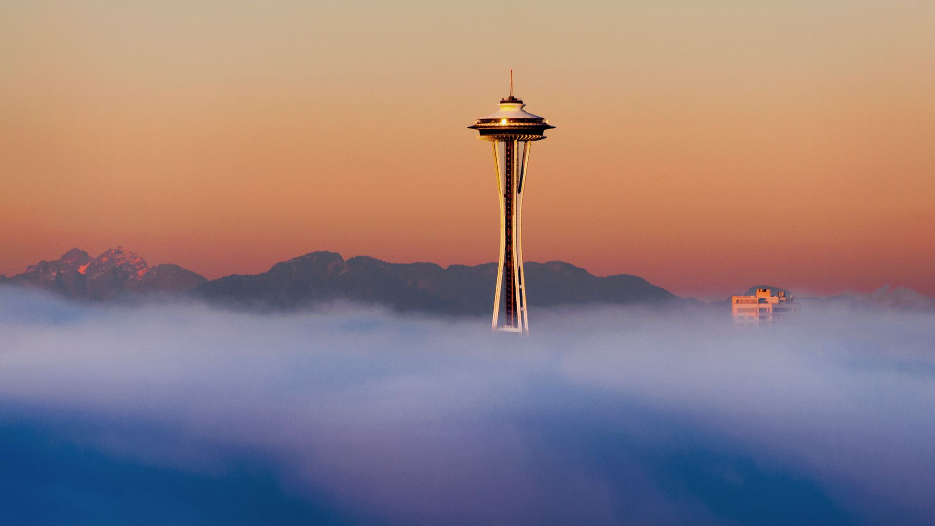 The Space Needle is seen above a blanket of fog. 