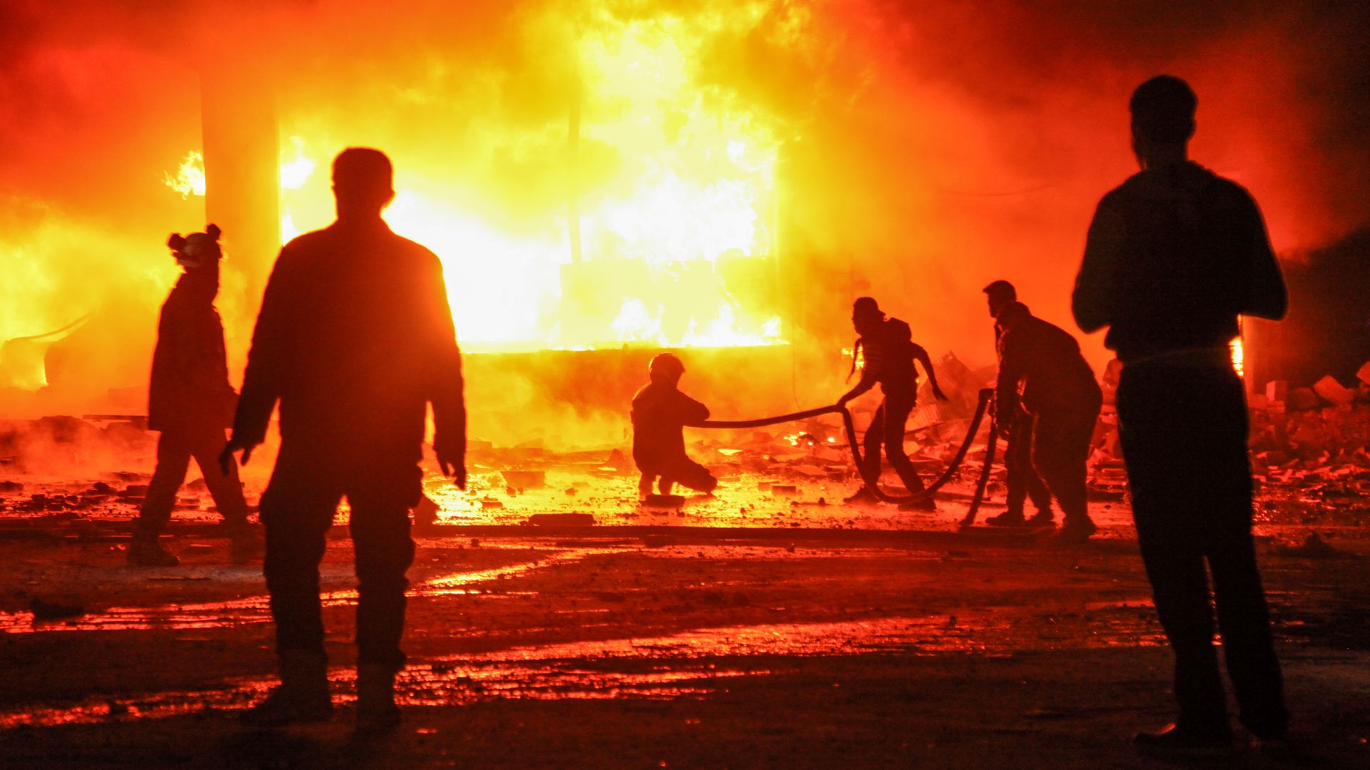Syrian volunteers put out an orange-colored fire.