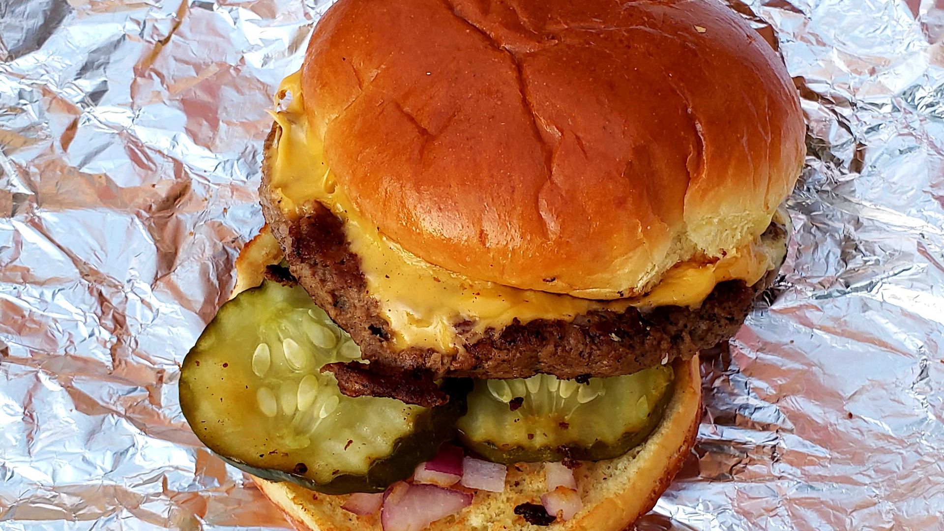 Photo of a hamburger on a foil wrapper. 
