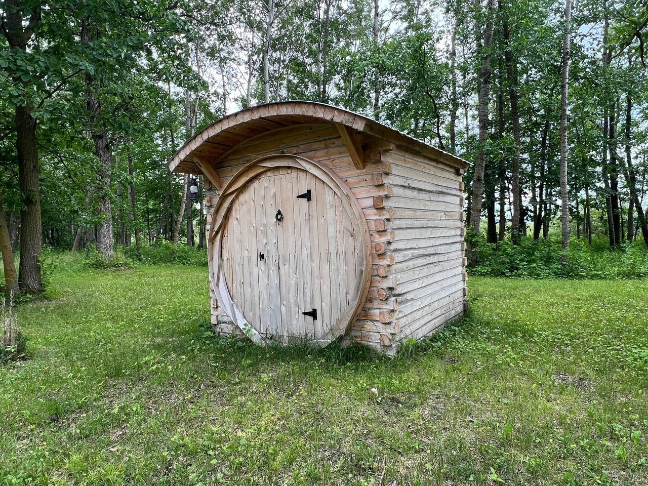 A cedar sauna with a round door.