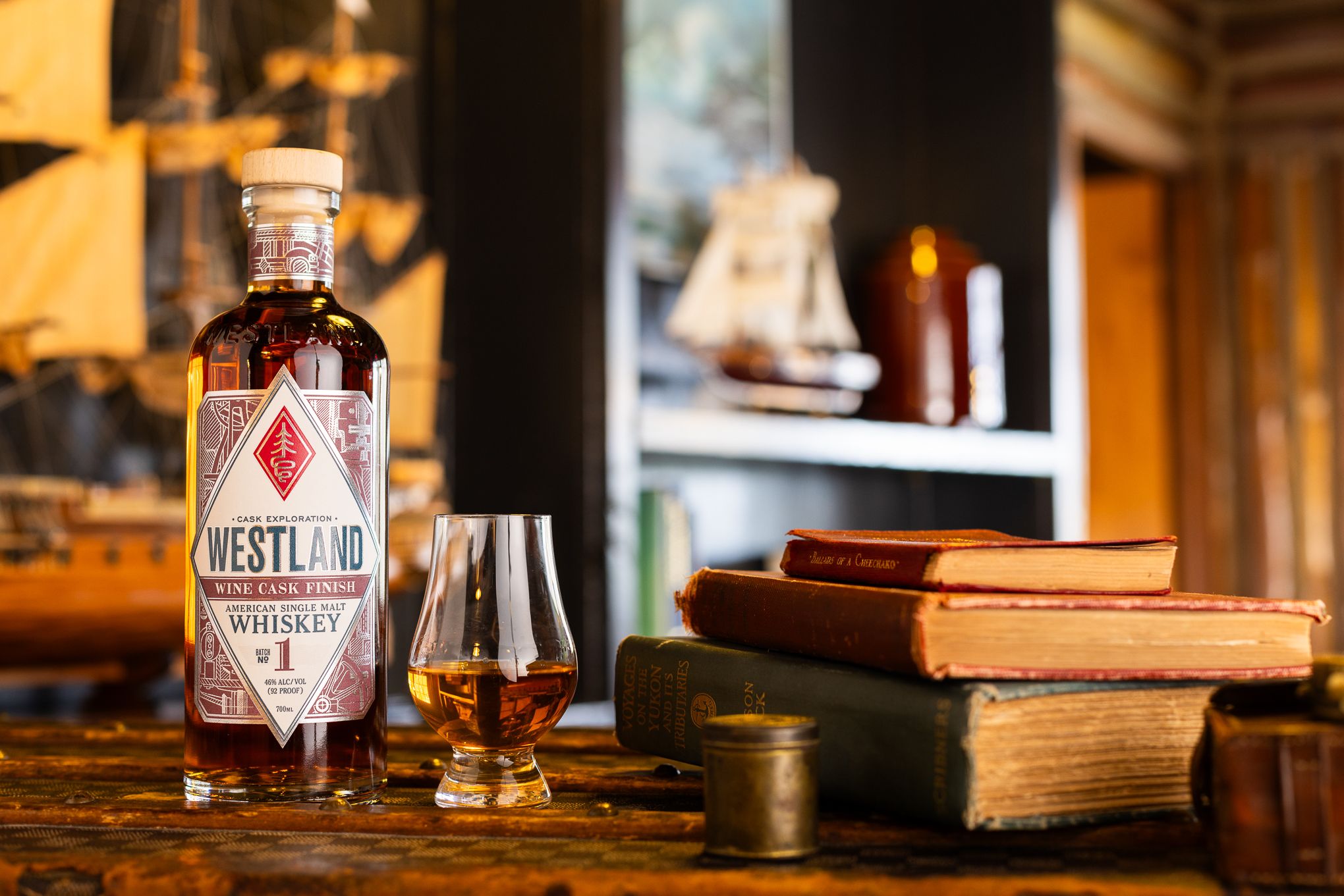 Westland's wine cask single malt next to a pile of books and a Glencairn curved glass filled with whiskey.