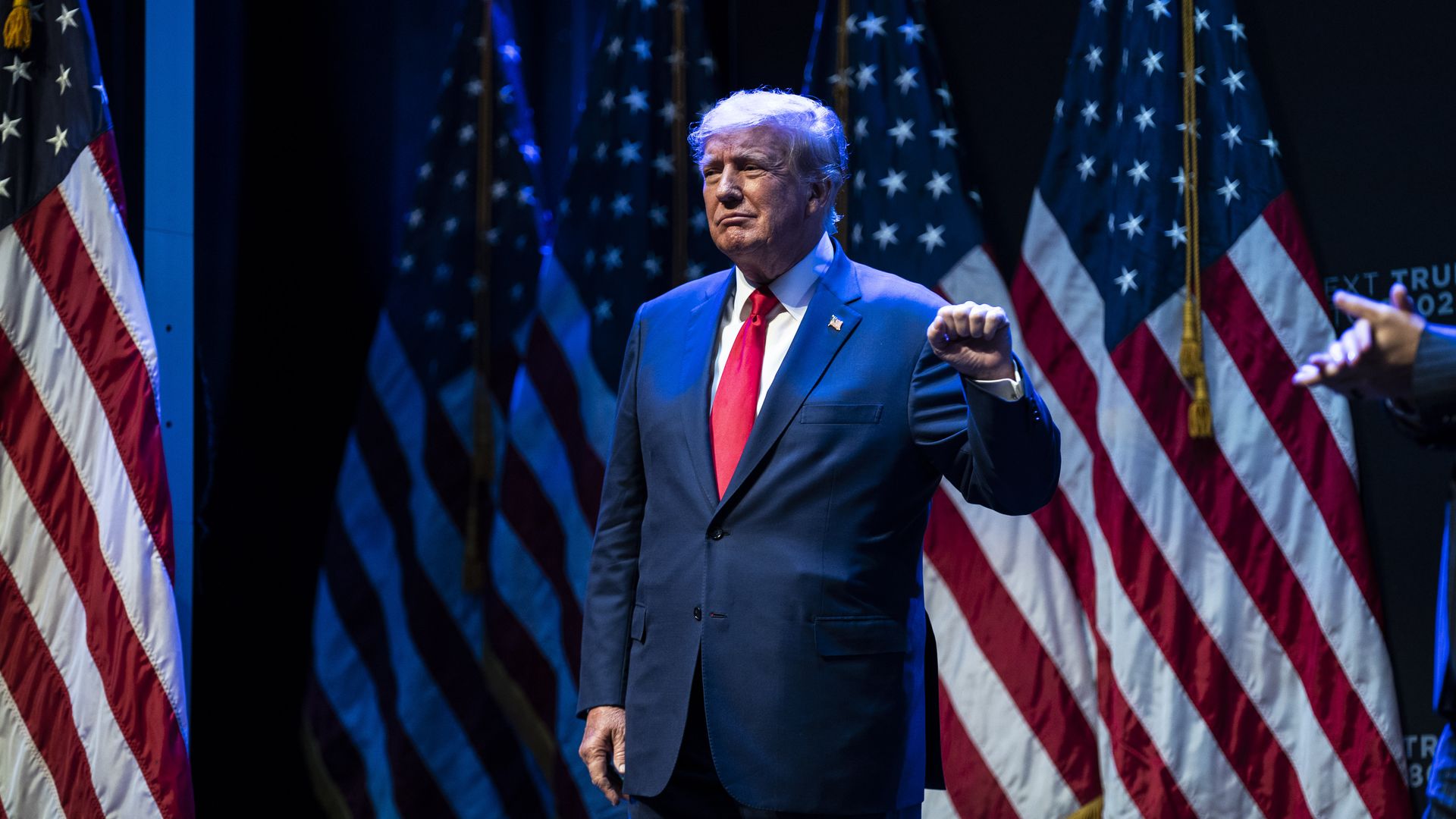 Photo of Donald Trump raising his left hand in a fist on stage at a rally
