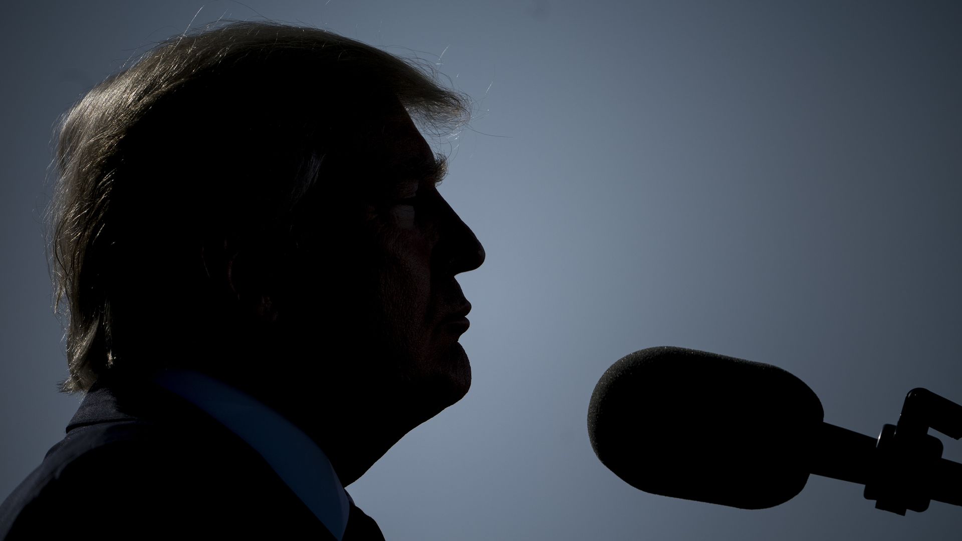 A silhouette profile image of President Donald Trump speaking into a microphone