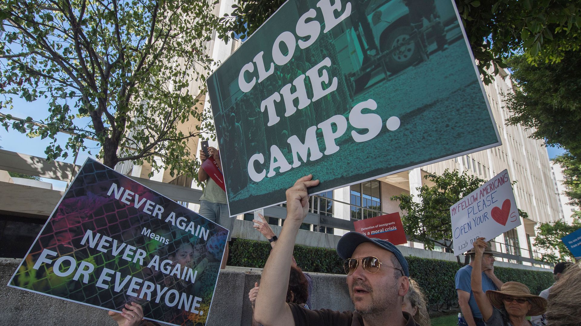 Protestors hold signs to close the detention camps
