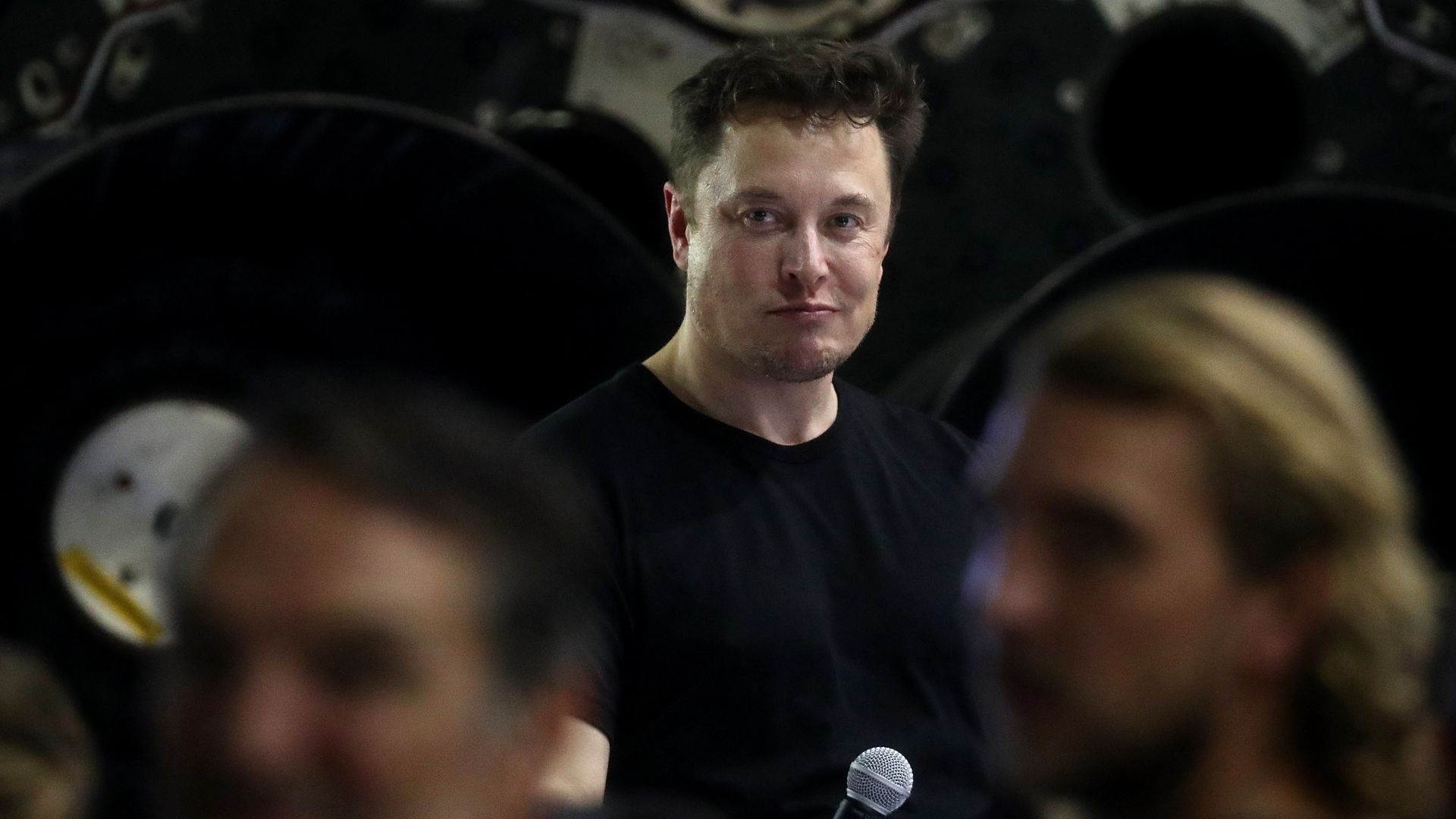 Elon Musk holds a microphone in a crowd. 
