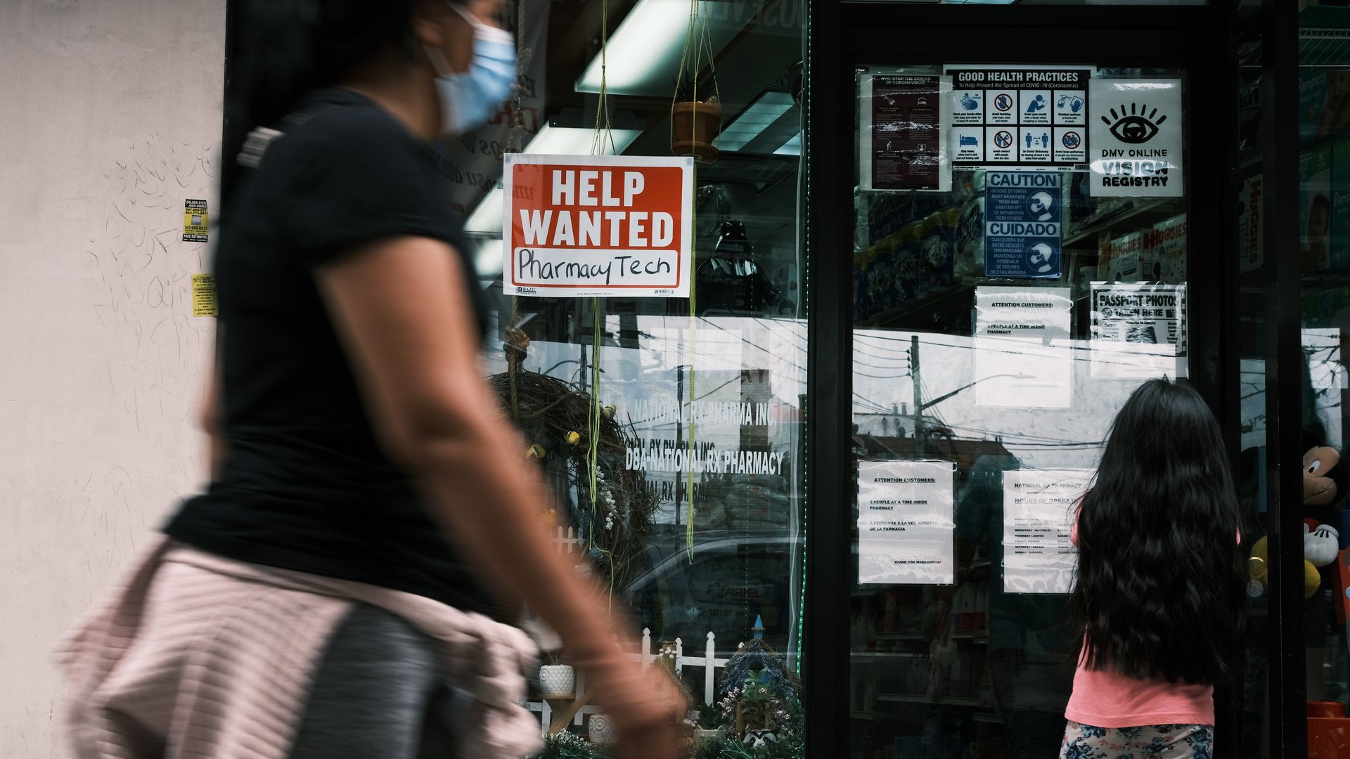A woman is seen walking past a "Help Wanted" sign in New York City.