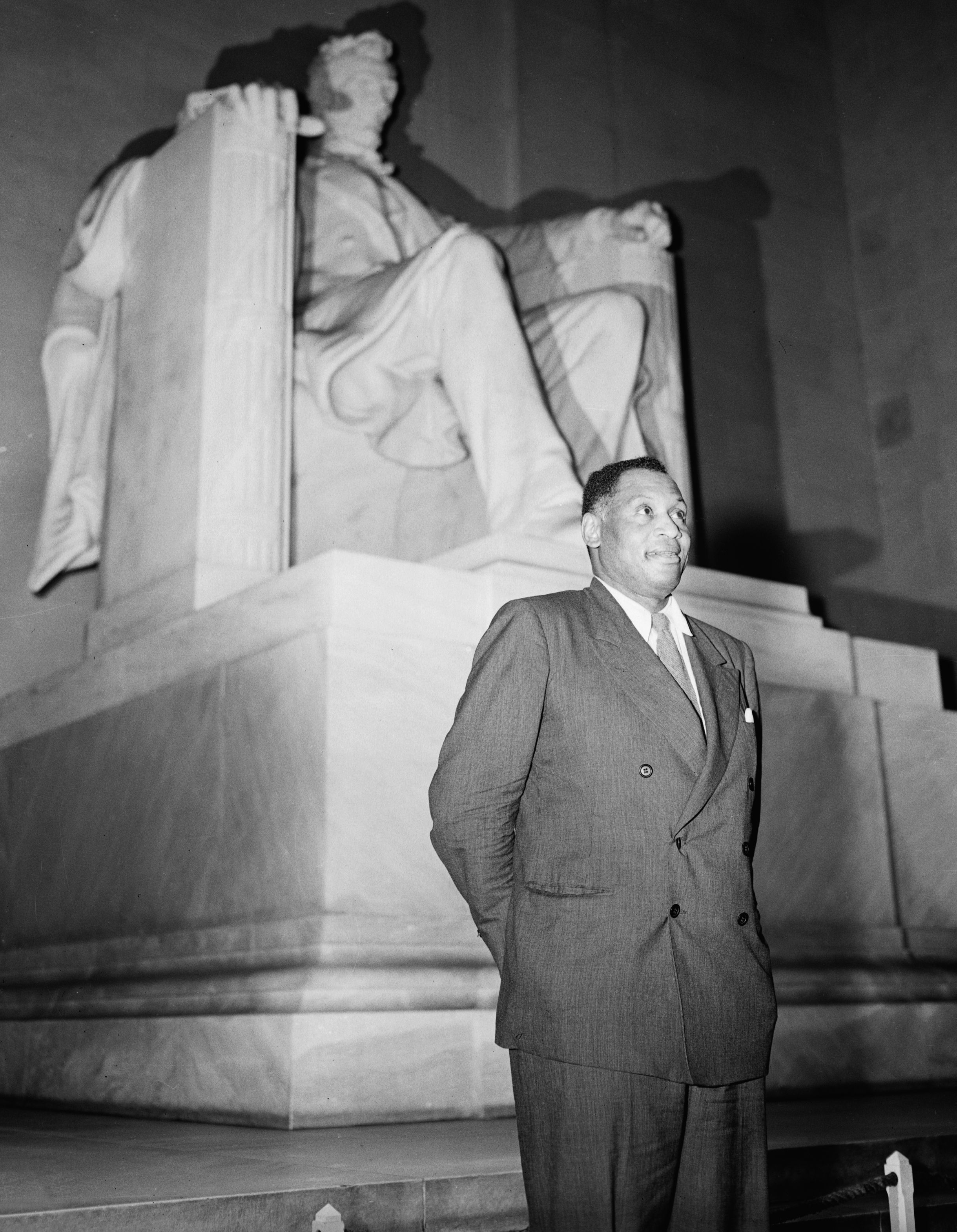 Singer and actor Paul Robeson stands before the statue of Abraham Lincoln in the Lincoln Memorial.