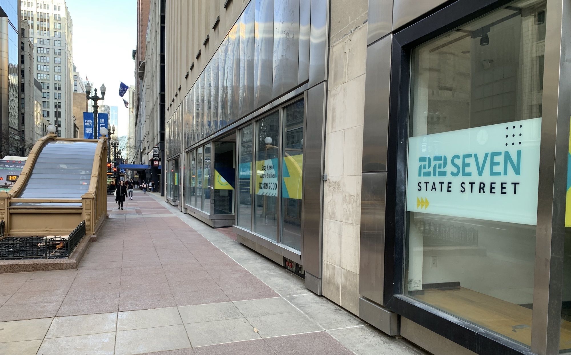 Entrance to underground train next to glass front building.