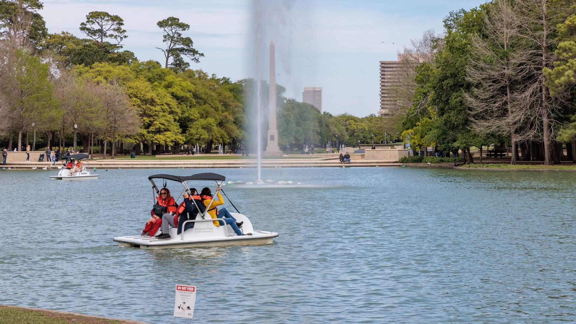 a family uses a paddle boat in Hermann Park