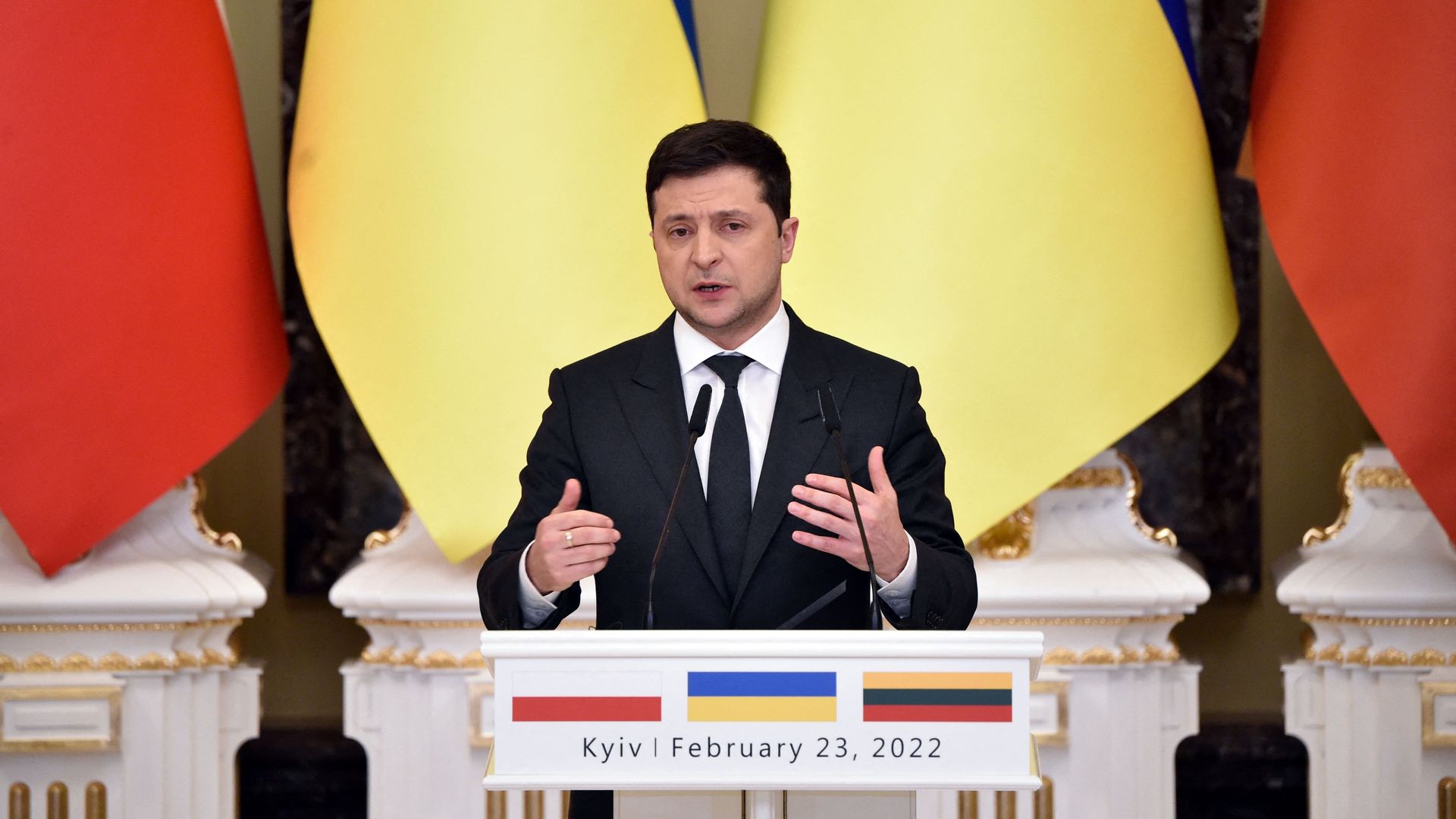 Photo of Volodymyr Zelensky speaking from a podium while gesturing with his hands in front of him
