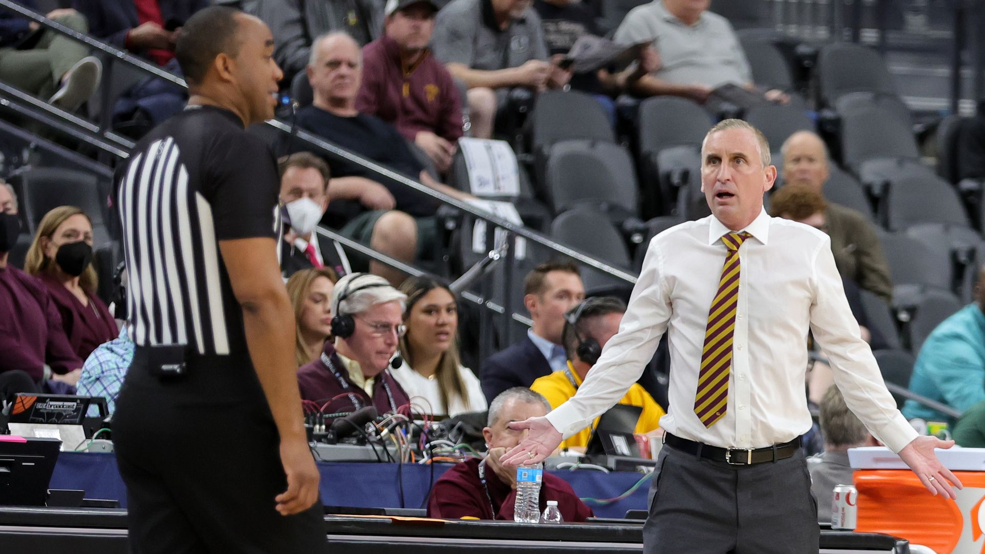 A coach talking to a referee on a basketball court.