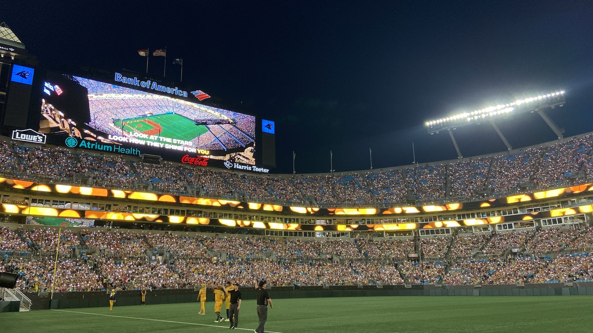 People hold their phones up with the flashlights on at Bank of America Stadium during a Savannah Bananas game.