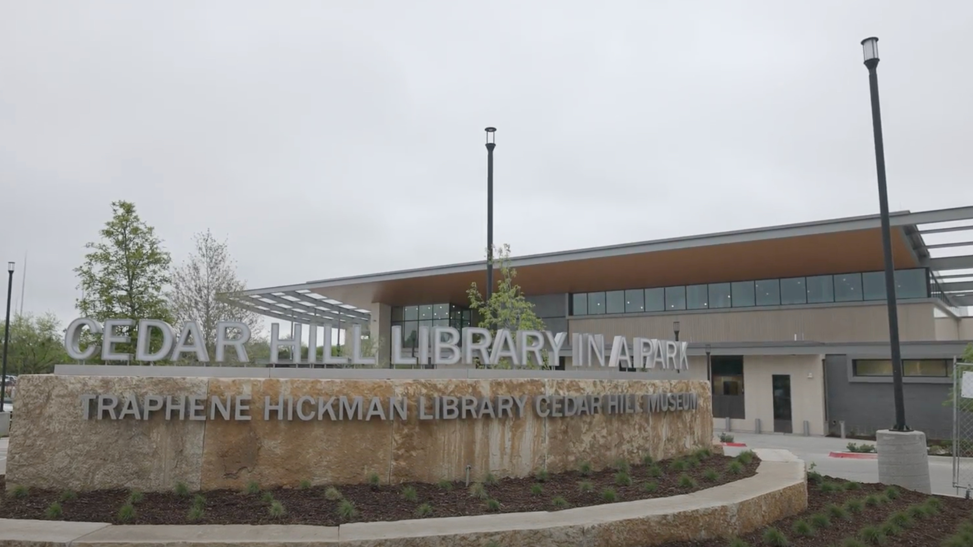 A sign saying "Cedar Hill Library In a Park" in front of a building