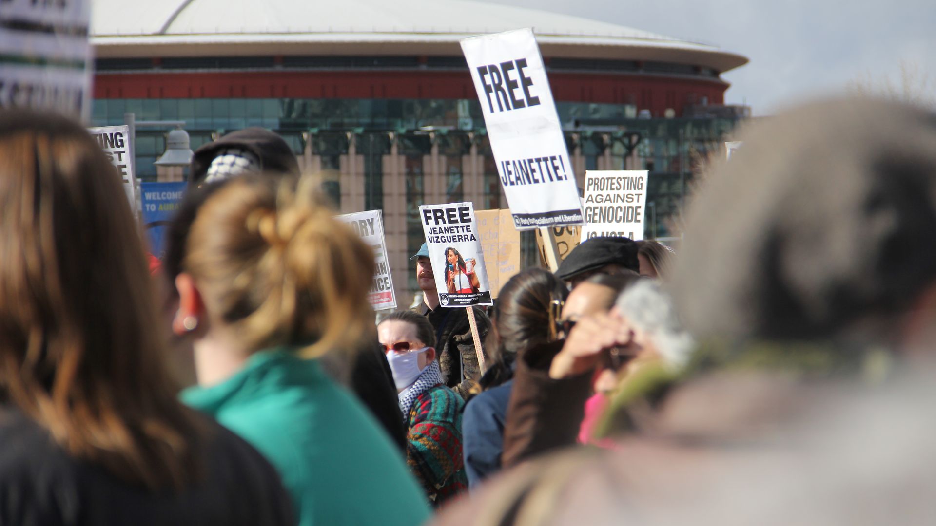 A crowd of people hold up signs including one reading FREE Jeanette. 