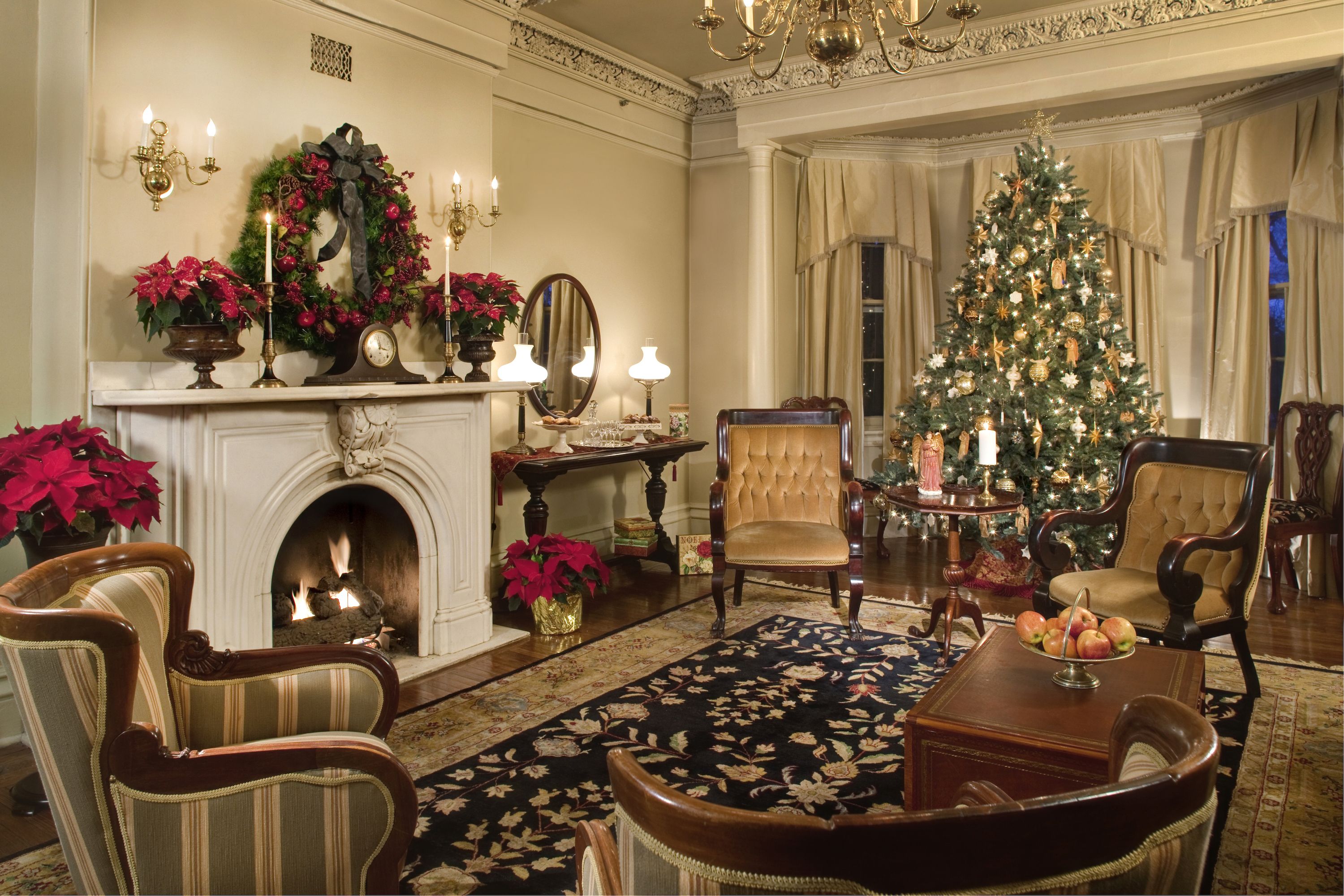 A historic home decorated for Christmas with a tree and ornaments on the mantle above a fire