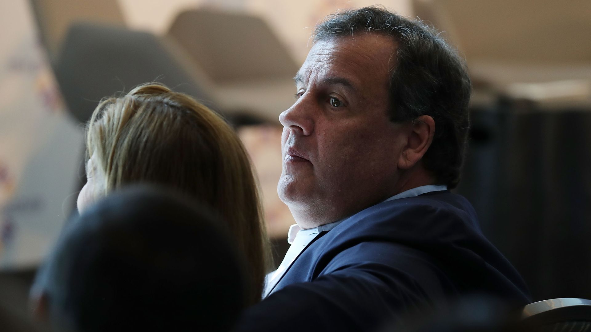 Former New Jersey Governor Chris Christie turns his head while seated