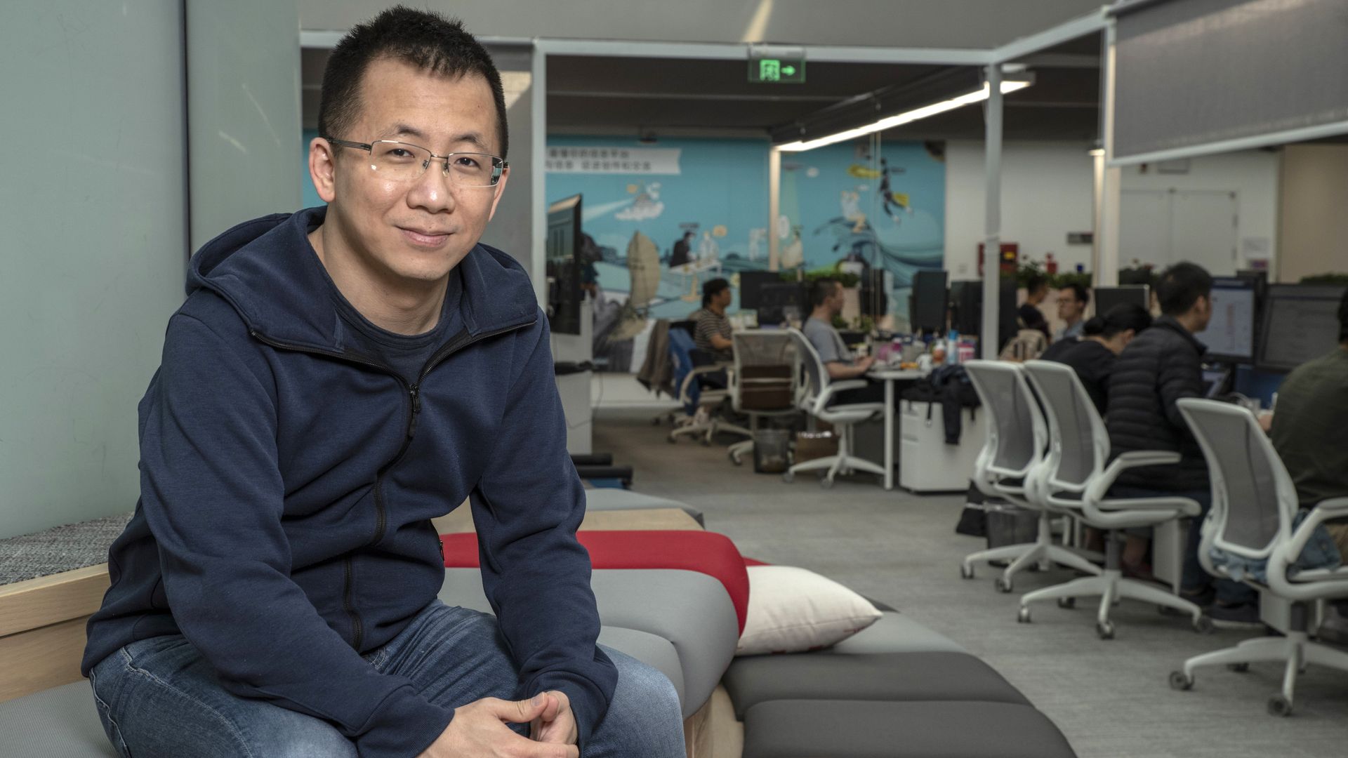 Bytedance CEO Zhang Yiming posing for a photograph in an office with people sitting at desks