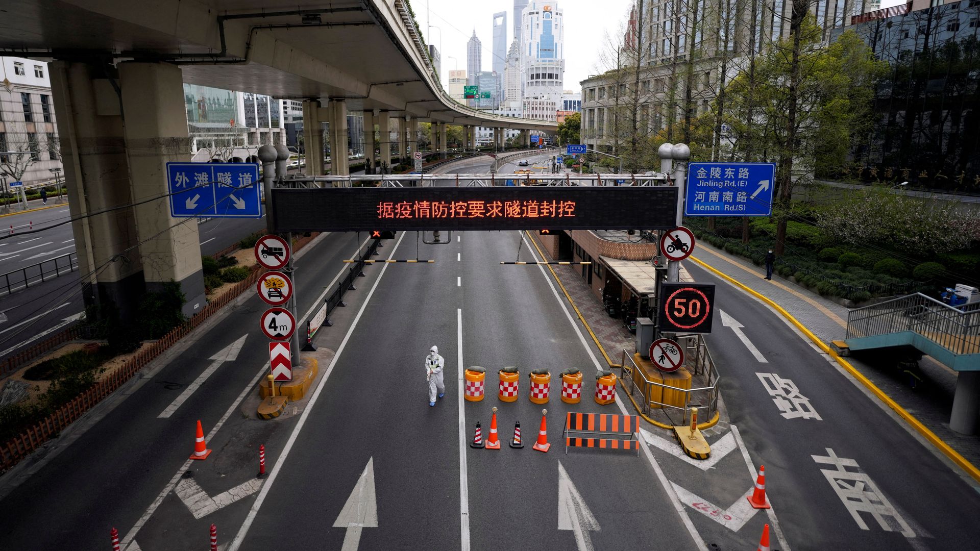 A worker in a protective suit walks today at the entrance to a tunnel leading to Shanghai's Pudong area.