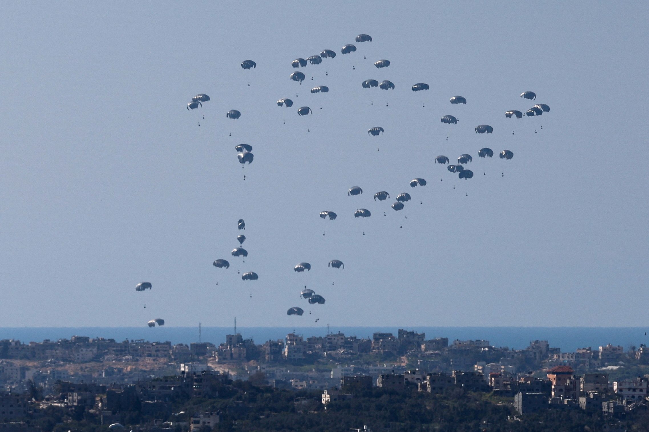 Packages fall towards northern Gaza, after being dropped from a military aircraft, amid the ongoing conflict between Israel and the Palestinian group Hamas, as seen from Israel's border with Gaza, in southern Israel, March 11, 2024.
