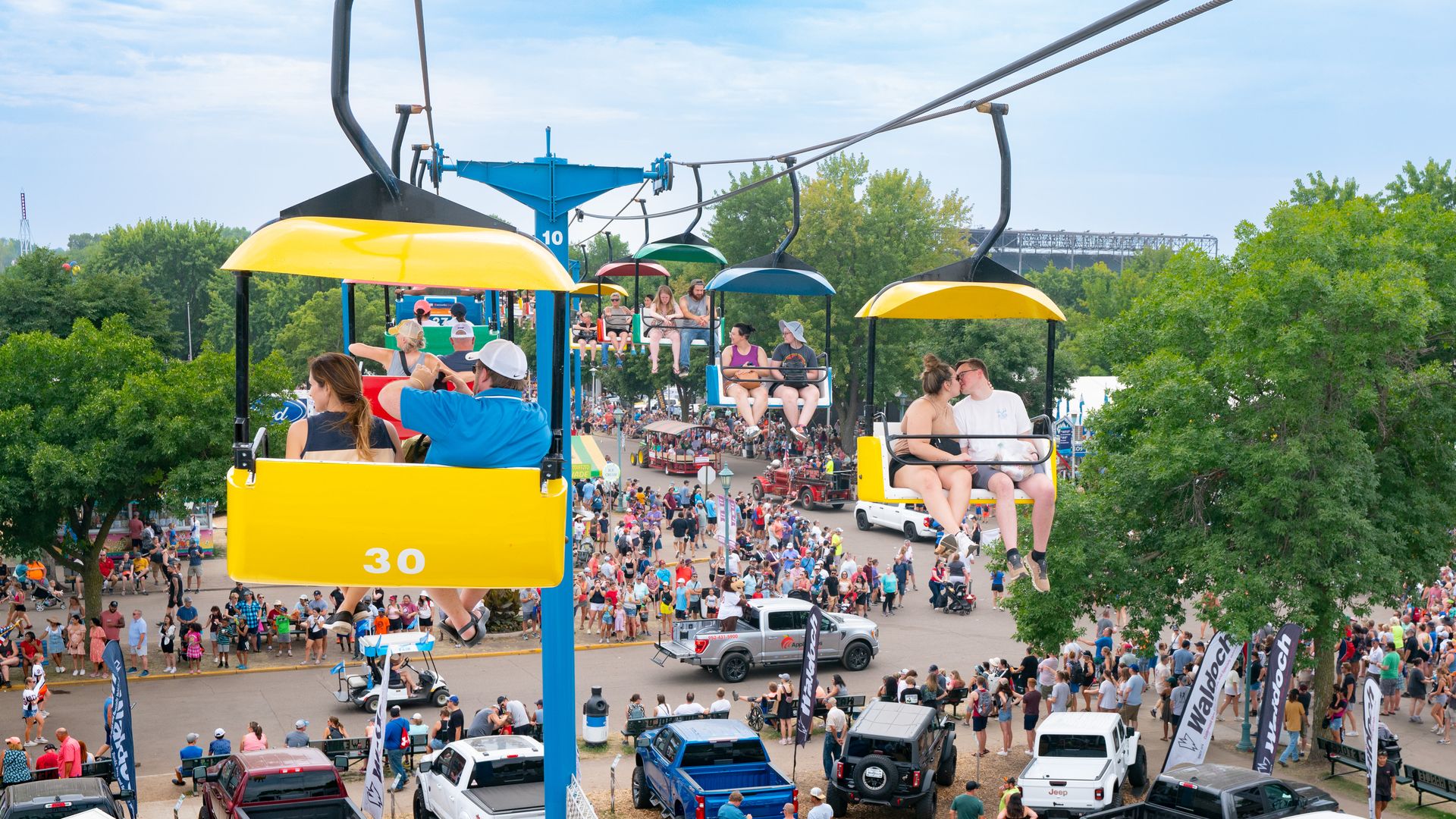 People sit on the state fair skyglider over crowds of people down below