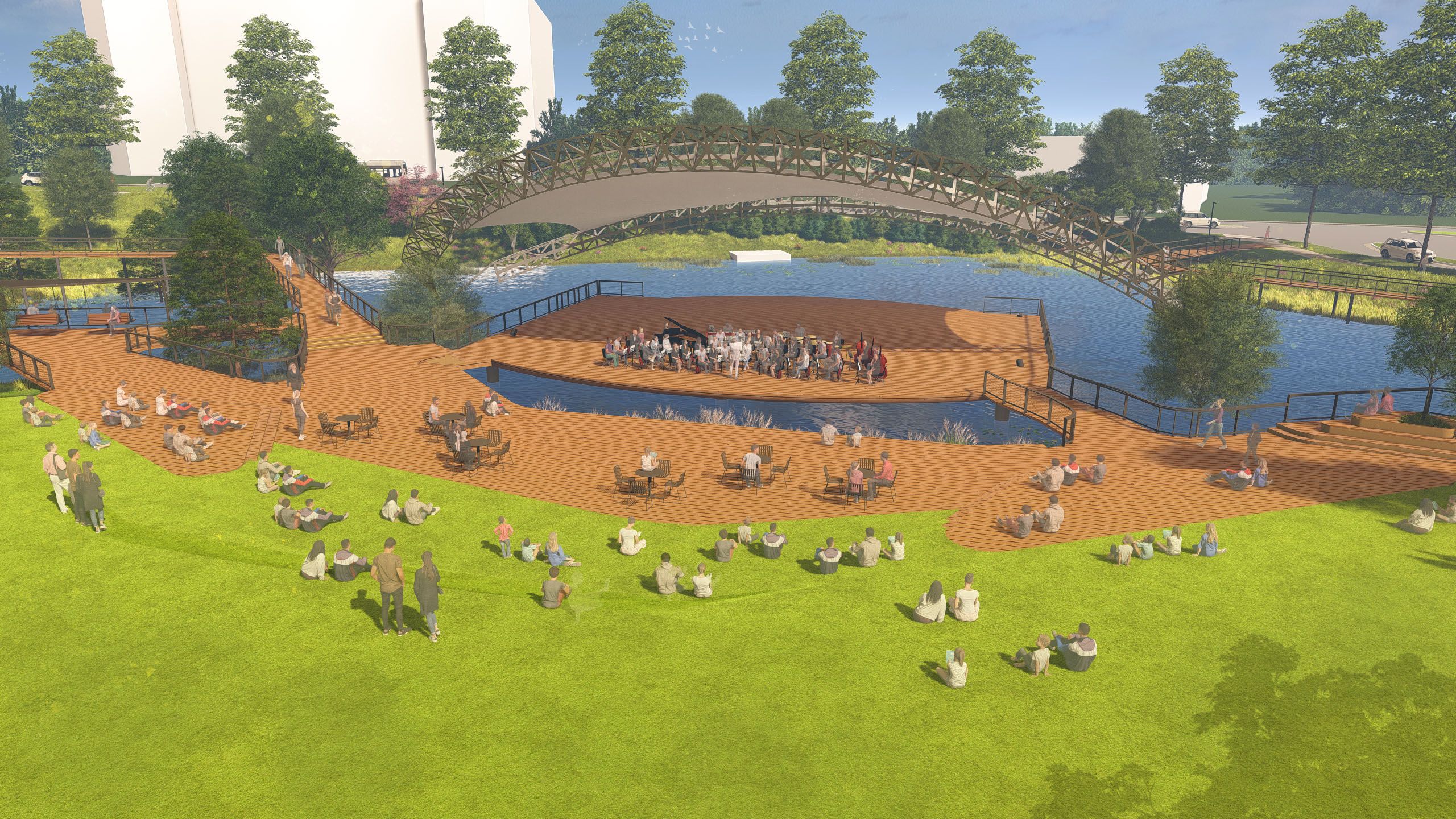 Outdoor concert in a park with people sitting on green grass and wooden decks surrounding a water stage. Trees and a wooden arch bridge frame the scene under blue sky.