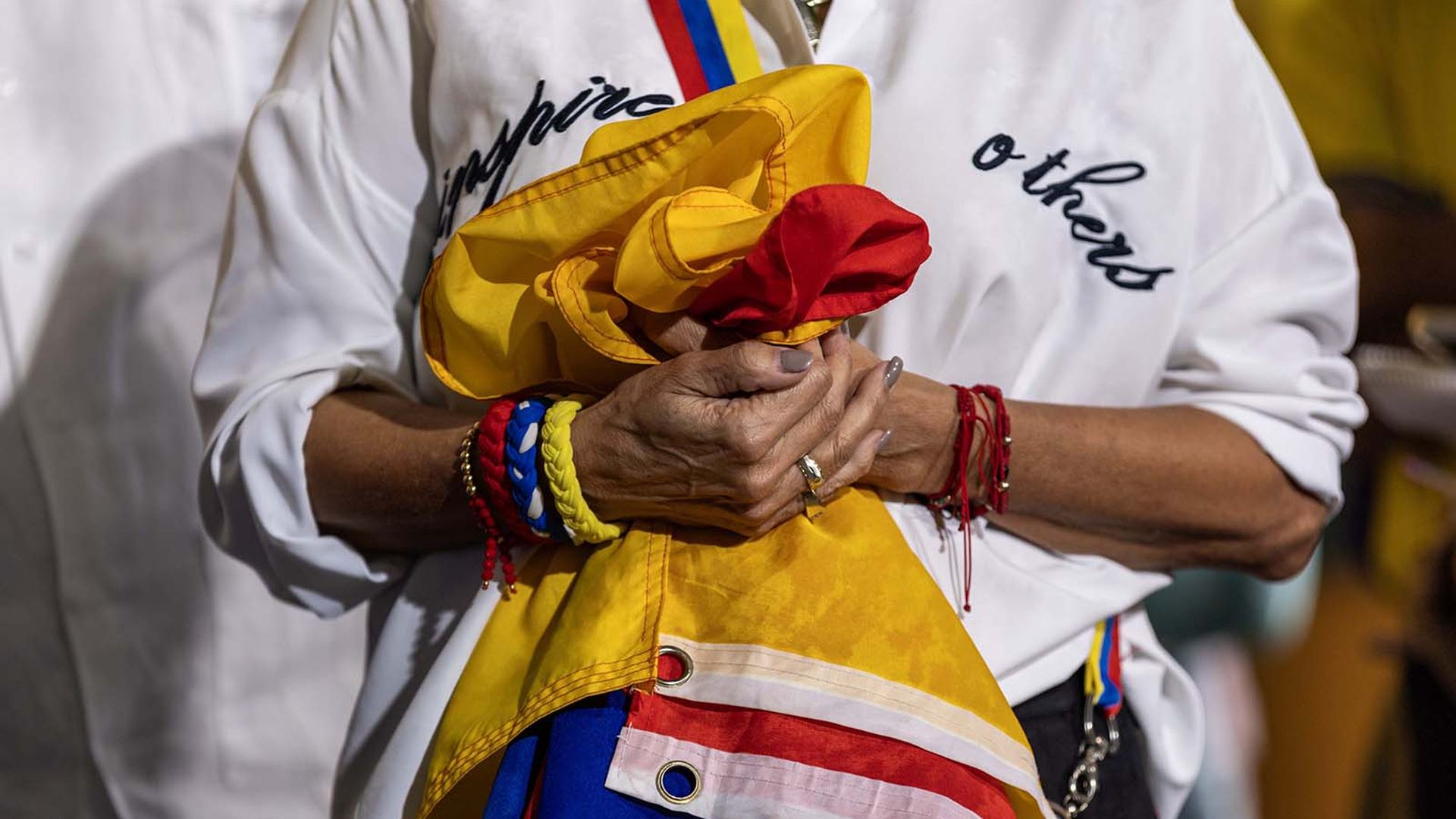 Woman holding a Venezuelan flag at a Venezuelan American Caucus press conference inside El Arepazo in Doral, Florida.