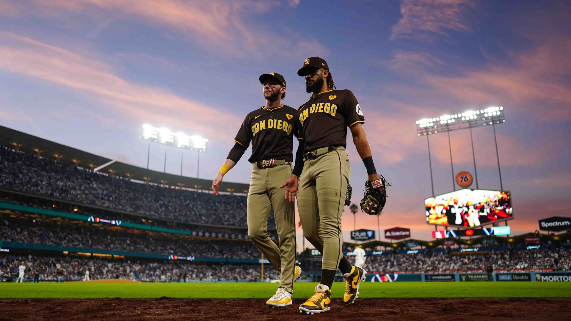 San Diego Padres players Jackson Merrill and Fernando Tatis Jr walk off the field at Dodger Stadium at sunset. 