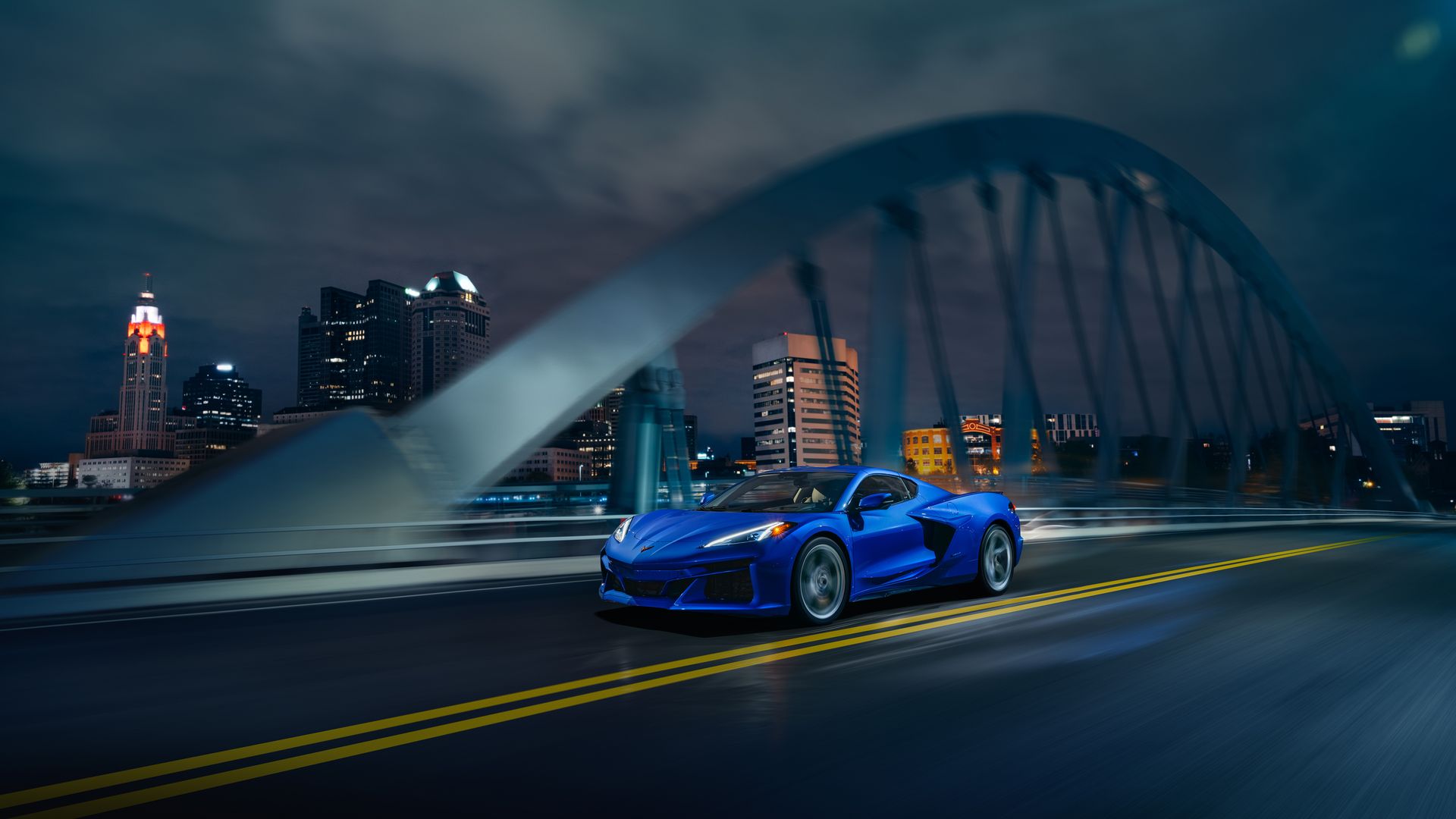 A blue Corvette E-ray driving over the Main Street Bridge at night in a heavily edited photo