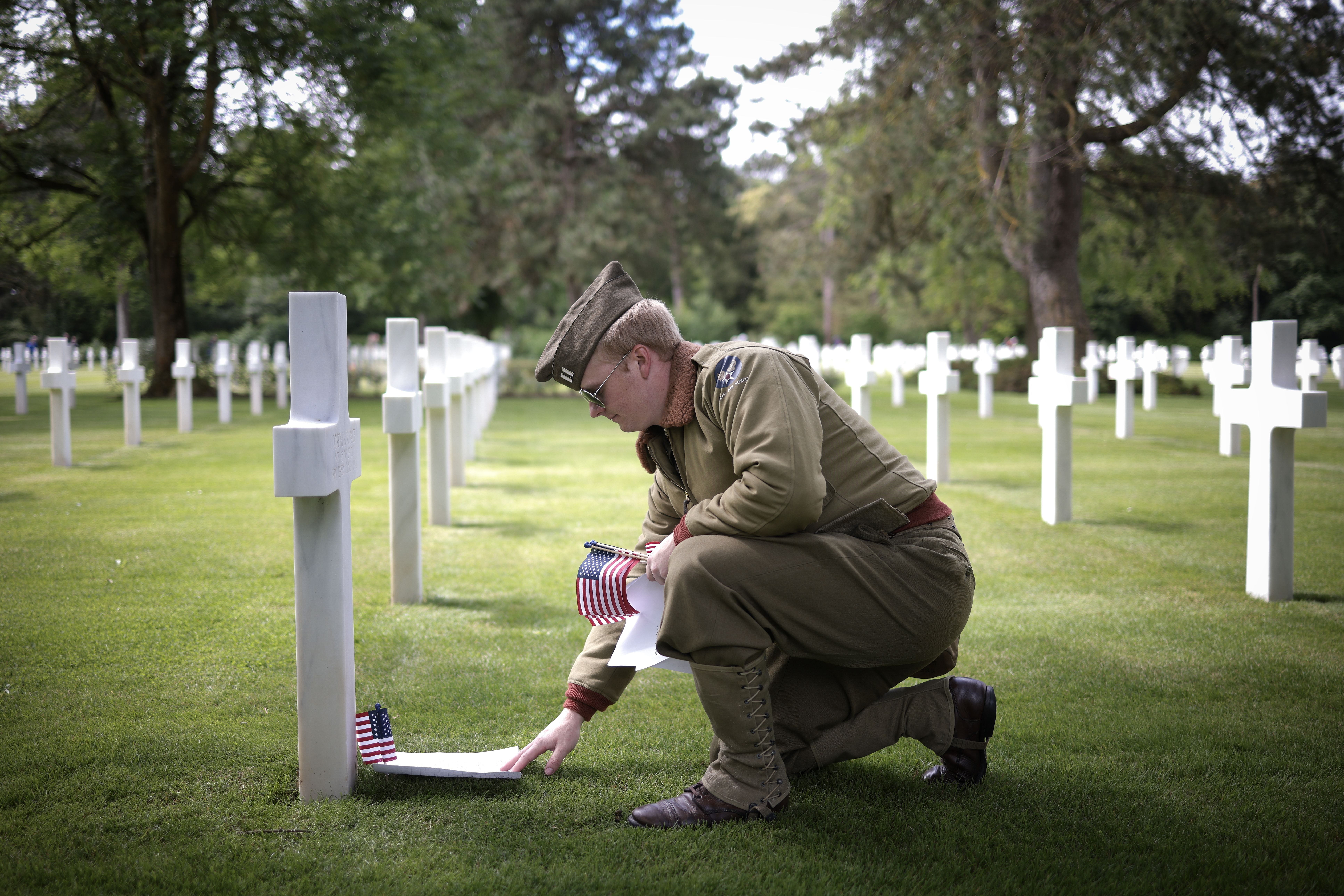 U.S. Air Force Capt. Ryan Knapp kneeling at the grave of a U.S. soldier killed in combat on D-Day at the Normandy American Cemetery on June 4 in Colleville-sur-Mer, France.