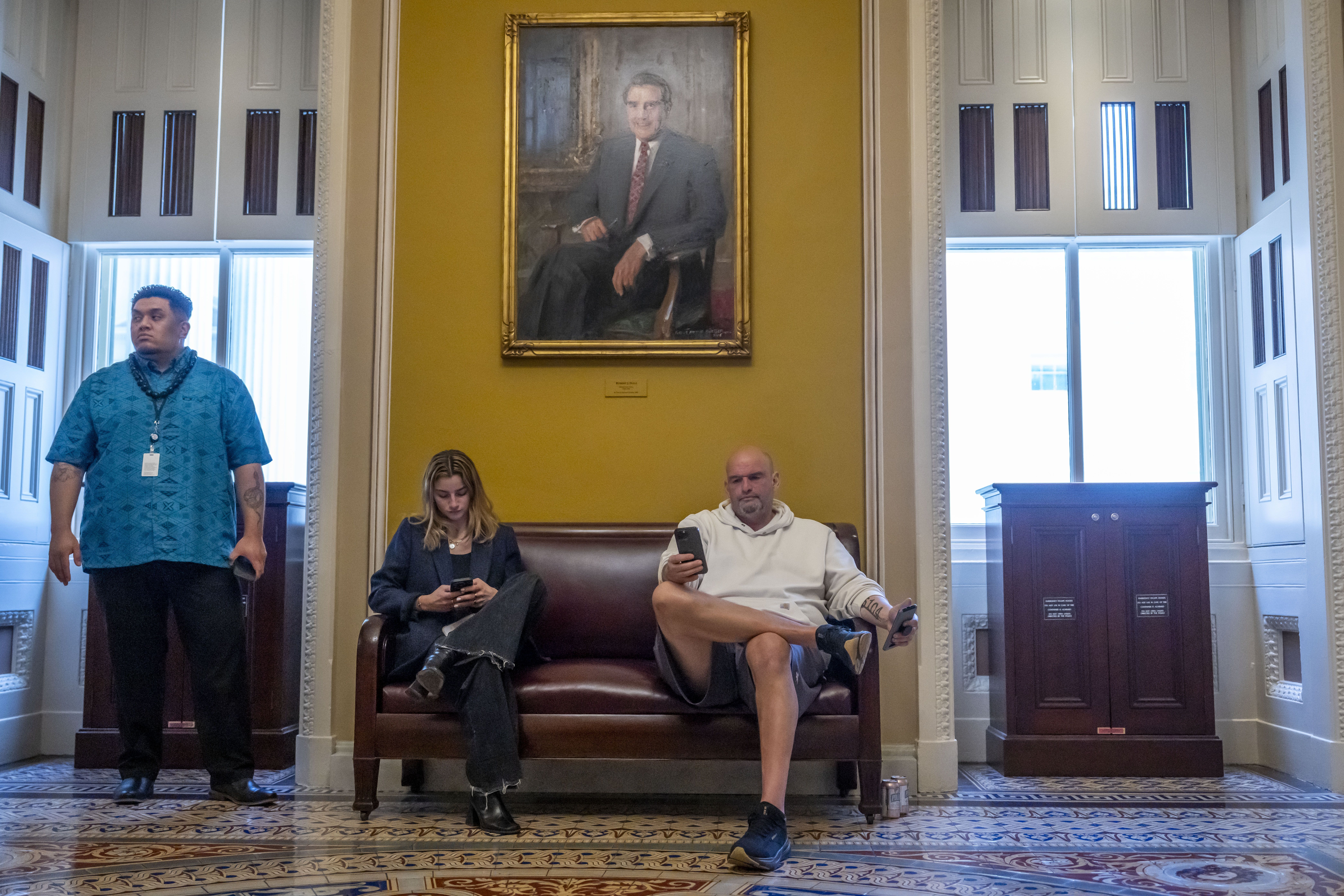 Sen. John Fetterman, D-Pa., sits under a portrait near the Senate chamber of former Senate Majority Leader Bob Dole, as the Senate works to avert a partial government shutdown ahead of the midnight deadline, at the Capitol in Washington, Friday, March 14, 2025. (AP Photo/Ben Curtis)
