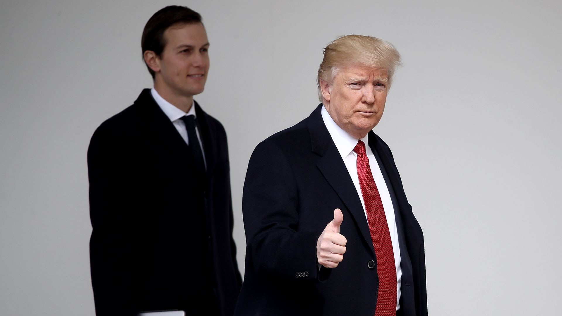 Donald Trump walking with a thumbs up with Jared Kushner walking behind him.