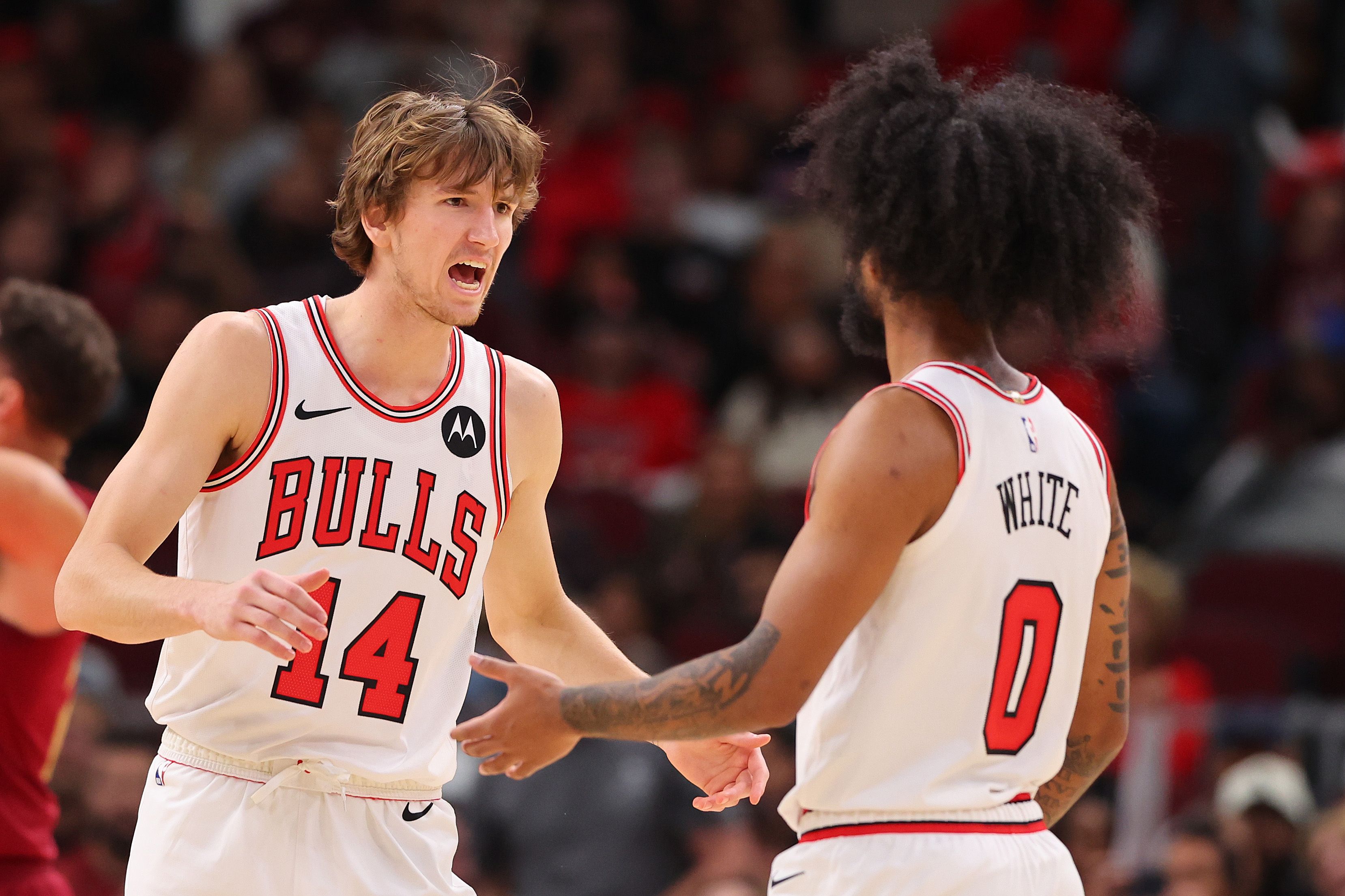 Photo of two basketball players talking and shaking hands on the court 