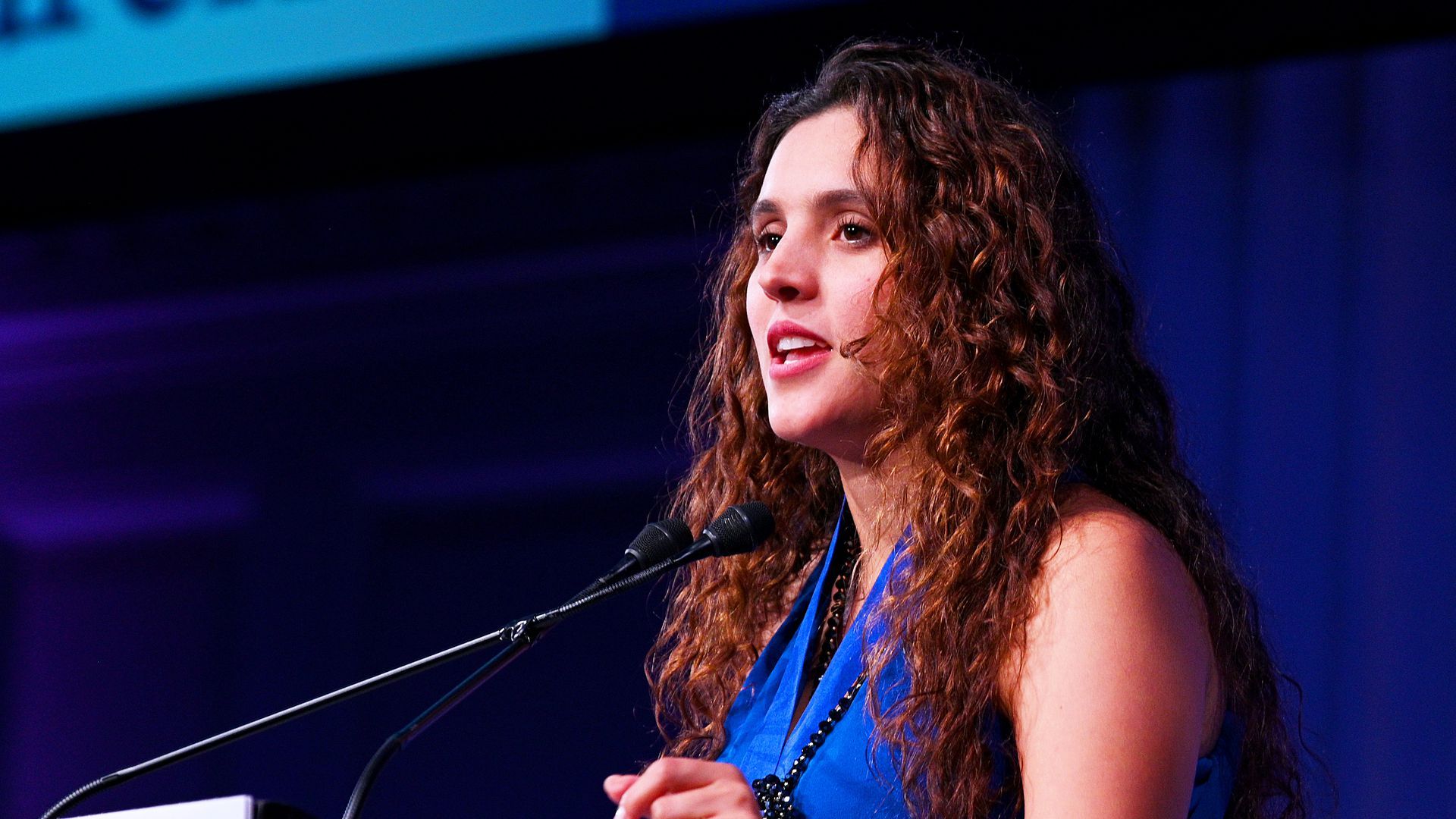 Brisa de Angulo speaks with a microphone in front of her