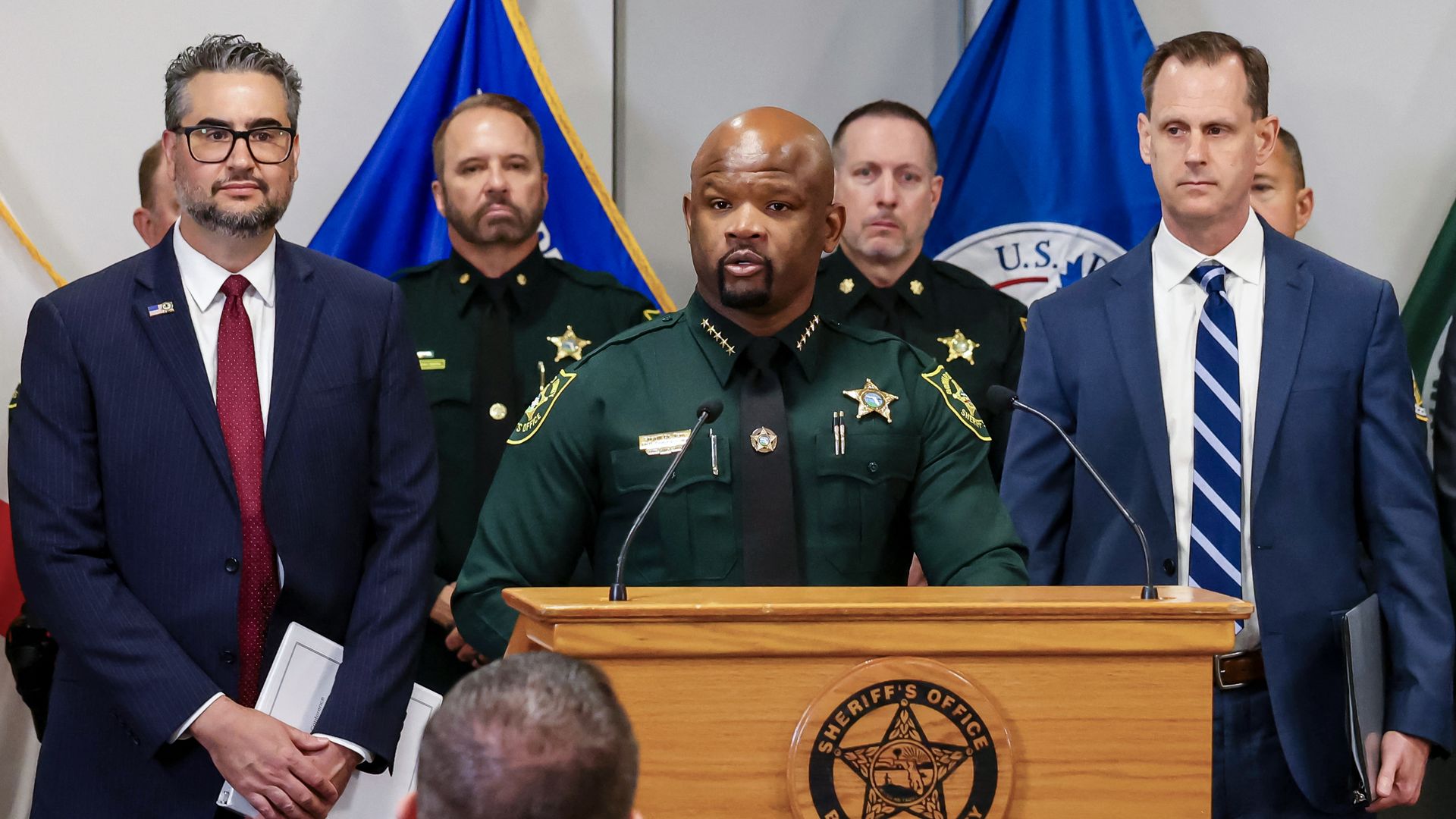 Broward Sheriff Dr. Gregory Tony speaks during during a press conference about MS-13 gang activity at the Broward County Sheriff's Office Research, Development and Training Center. Officers stand behind him while a man stands on either side of him at the podium