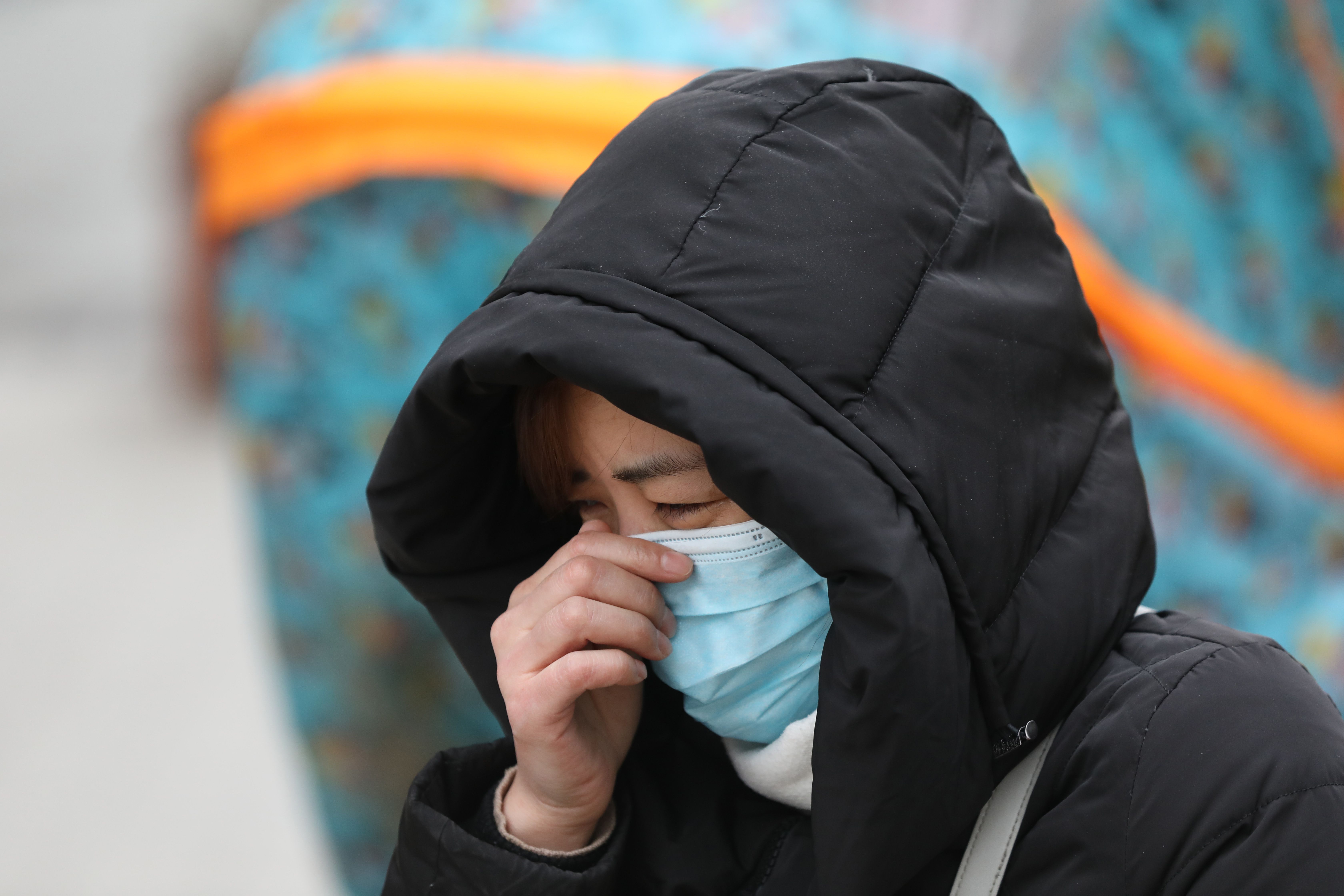 A woman cries at the vigil, wearing a coat and a protective face mask