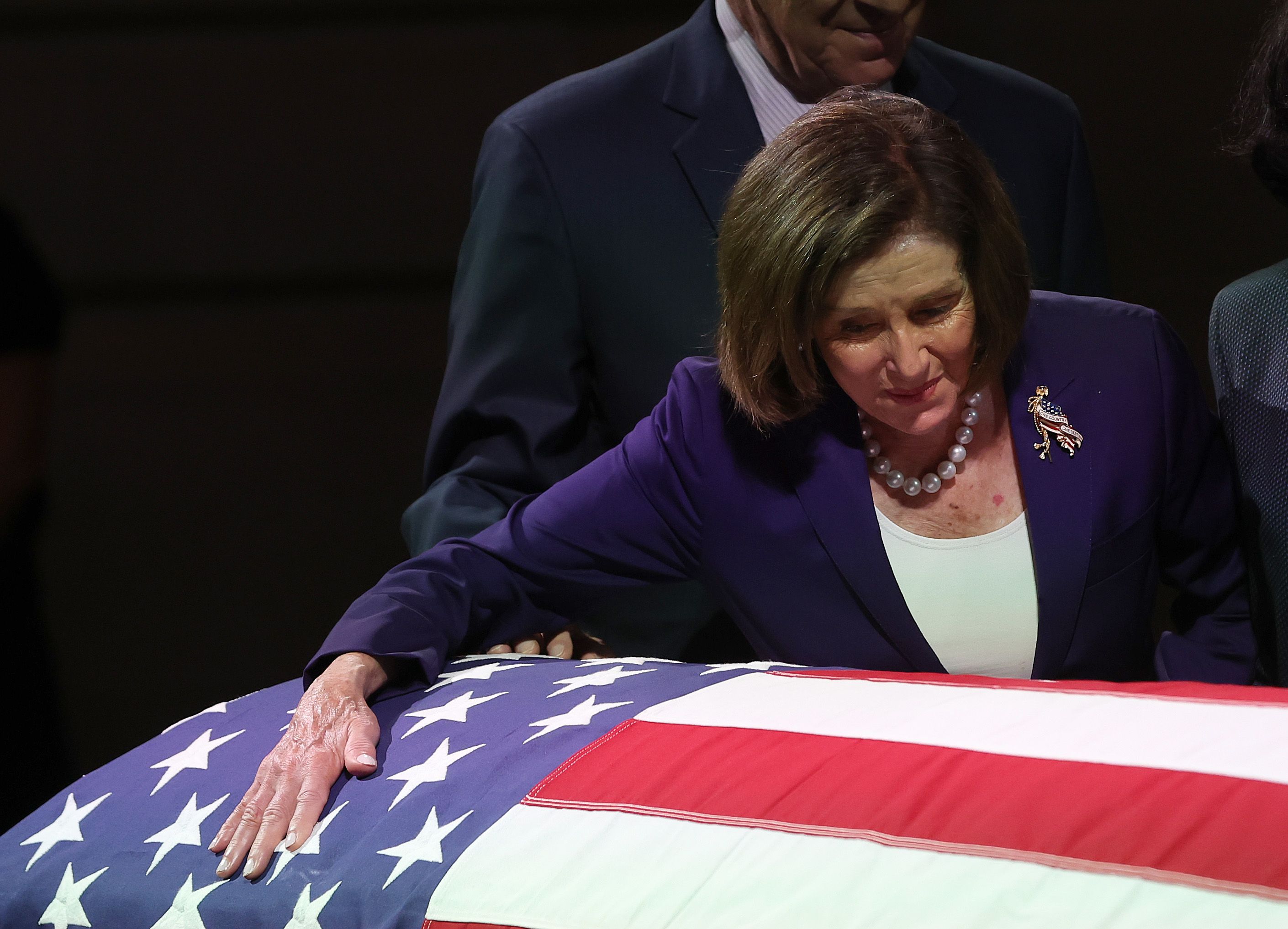 Nancy Pelosi leans on the casket with Paul Pelosi, her husband, standing behind her