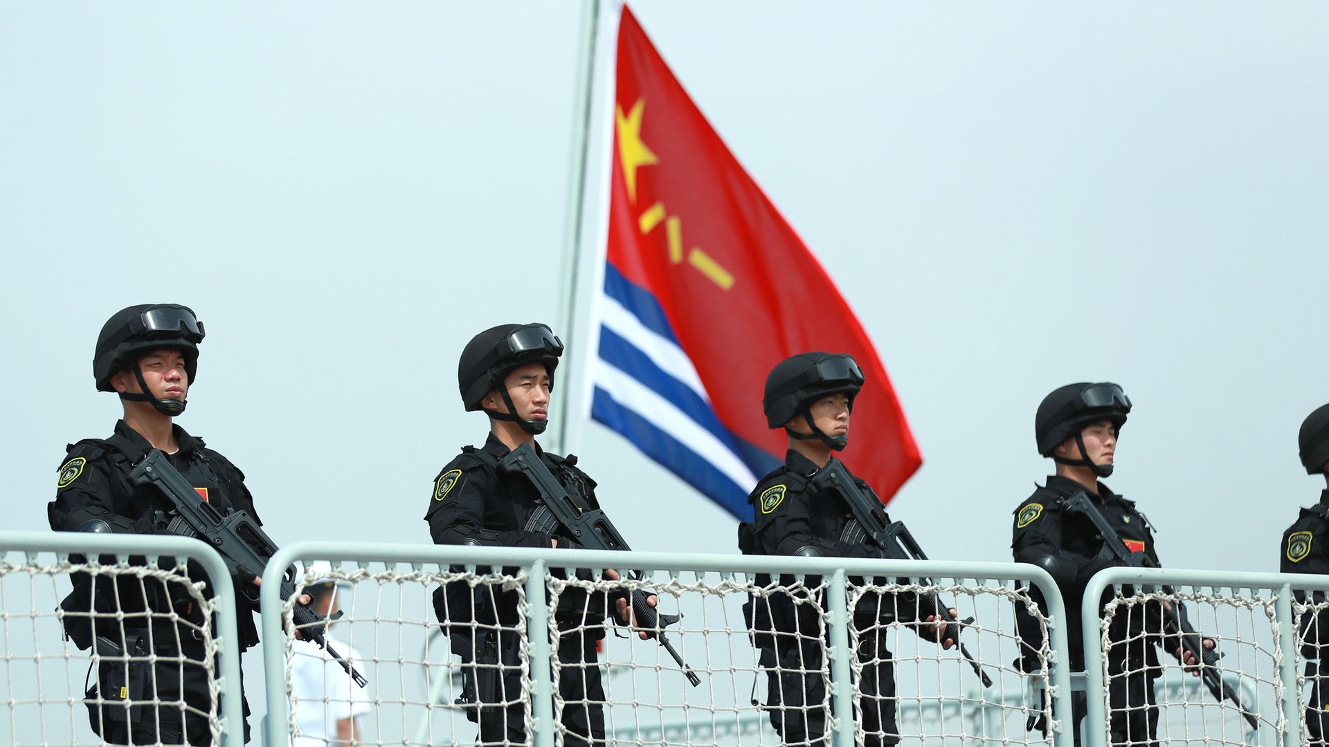 Members of the Chines Navy stand on the deck of a navy ship.