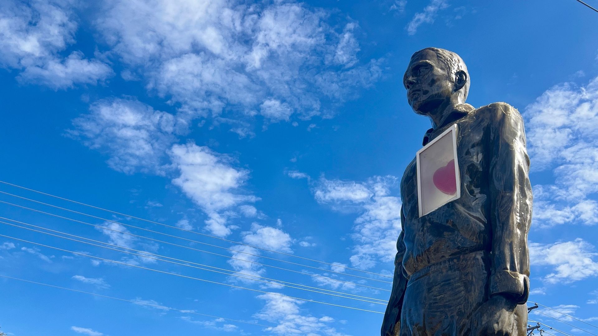 A photo of a sculpture of a man with his heart behind glass