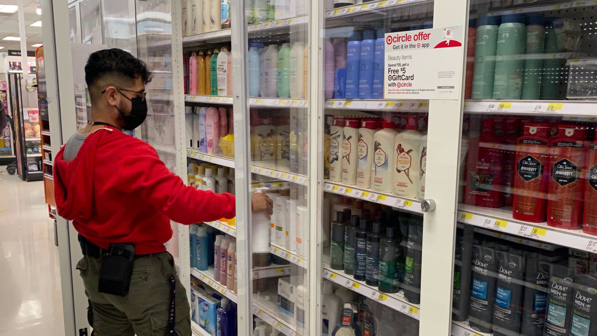 Employee stocks items behind locked glass shelves in retail store.