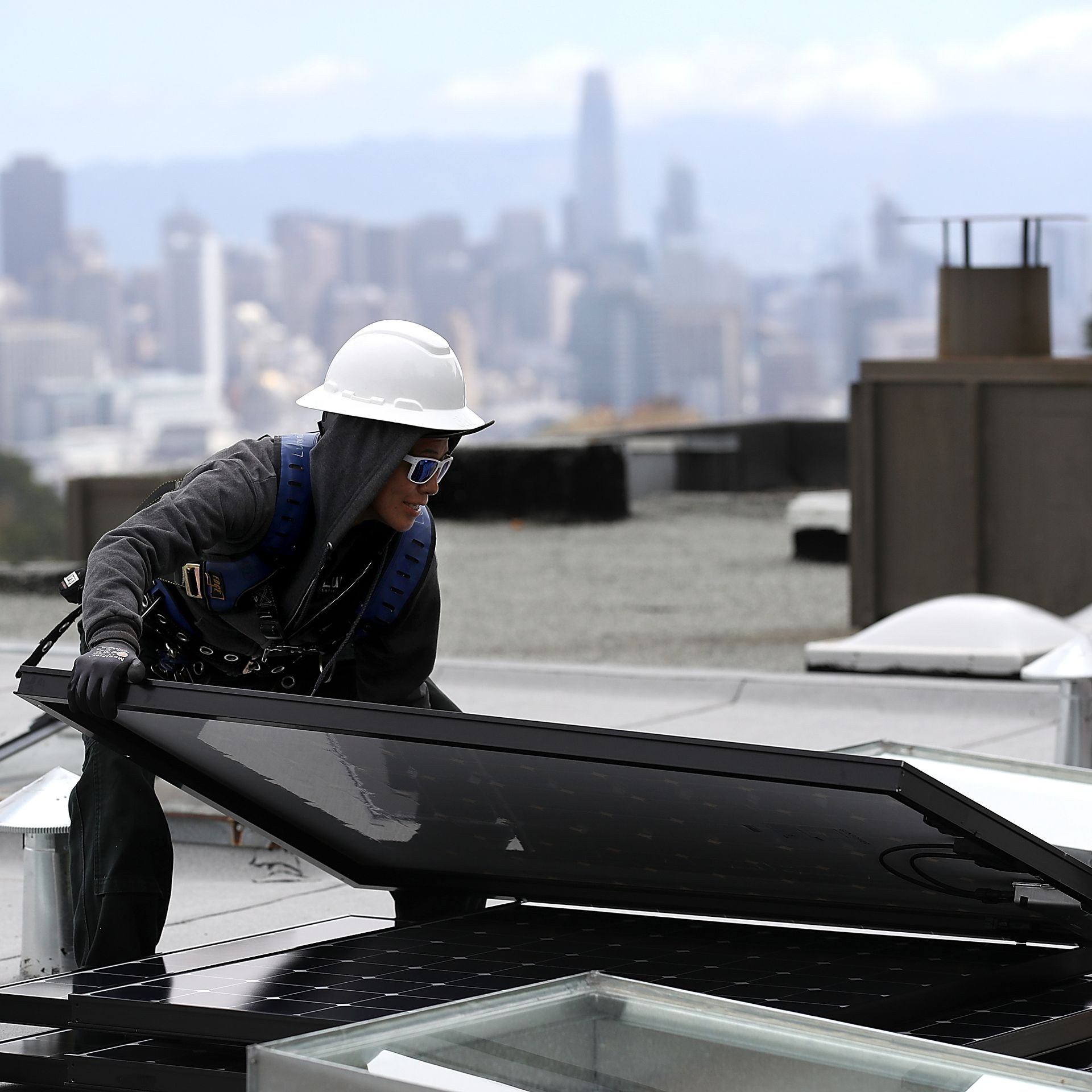 Luminalt solar installers Pam Quan moves a solar panel during an istallation on the roof of a home on May 9, 2018 in San Francisco, California.  