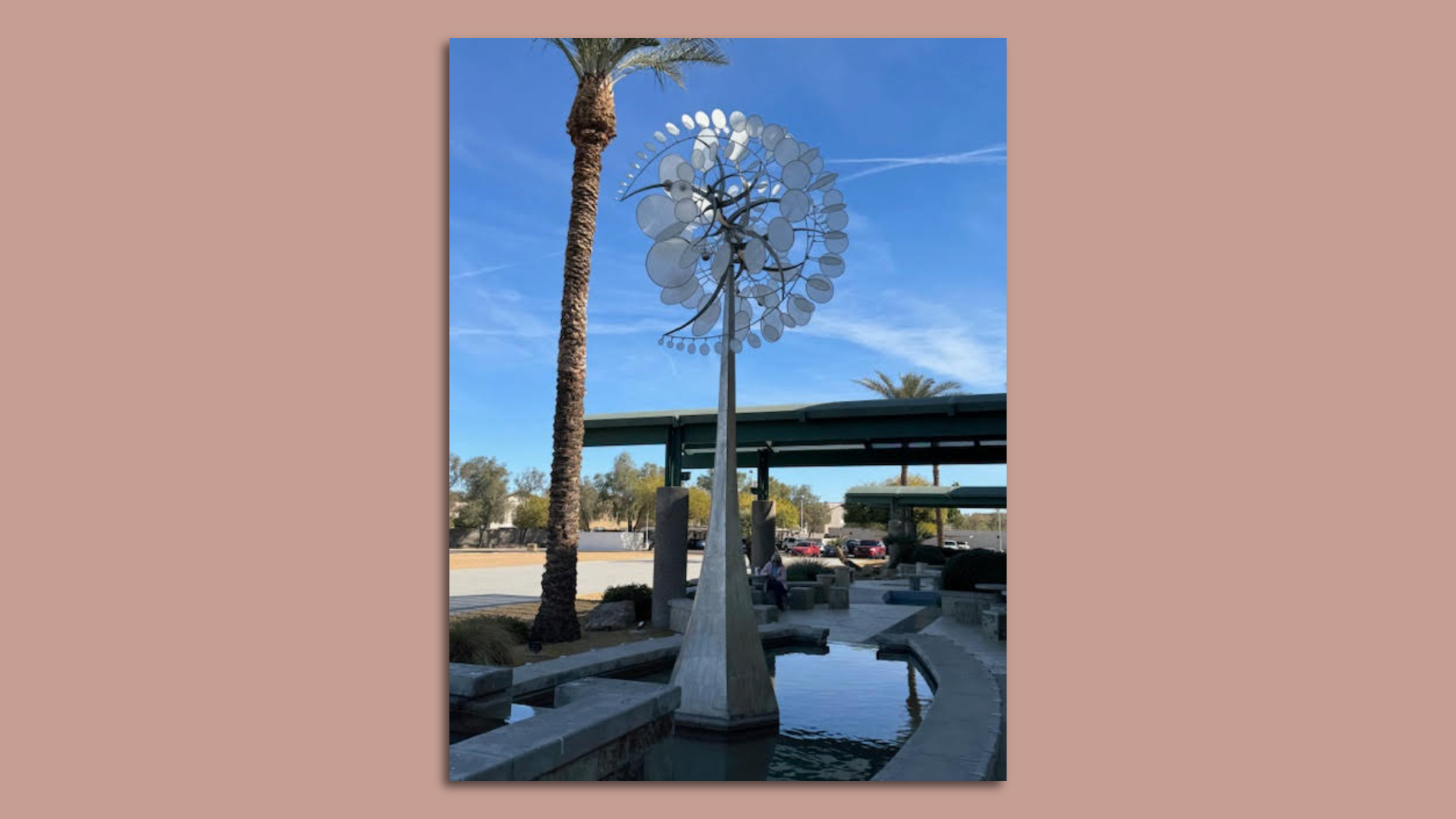 An assortment of silver circles of various sizes arranged in a crescent formation atop a silver spire. 
