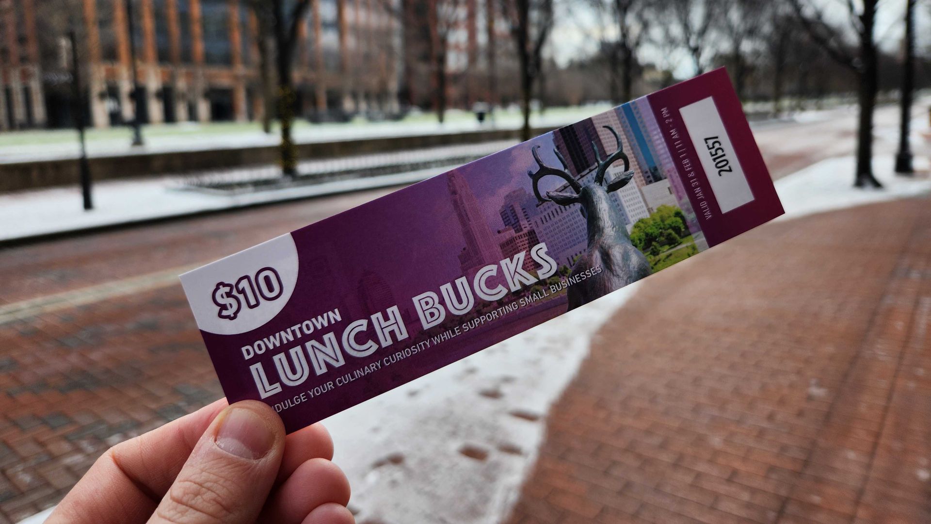 Holding up a $10 lunch voucher ticket.