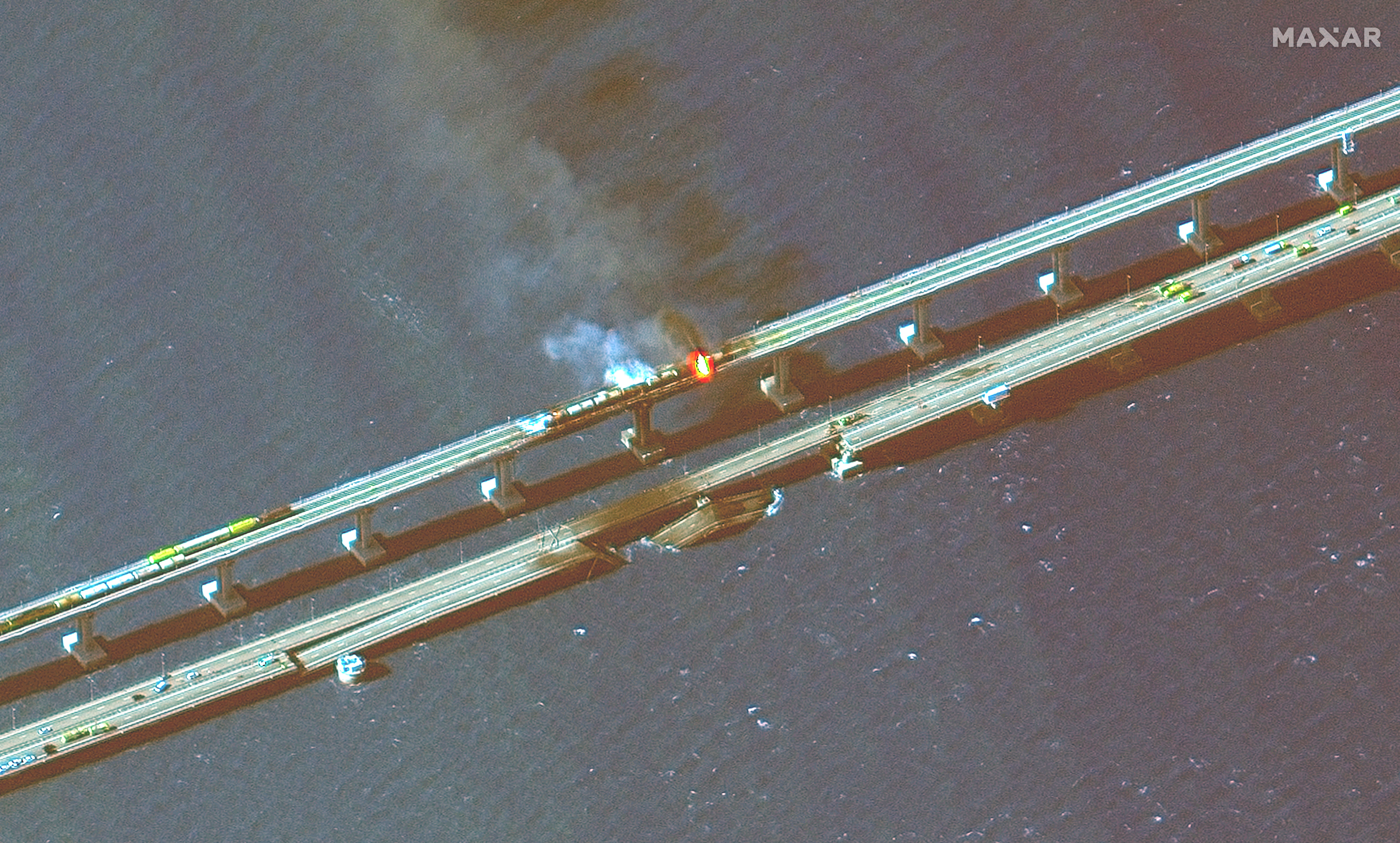 A section of the Kerch Bridge collaposed into the Kerch Straight while another portion is on fire after an explosion.