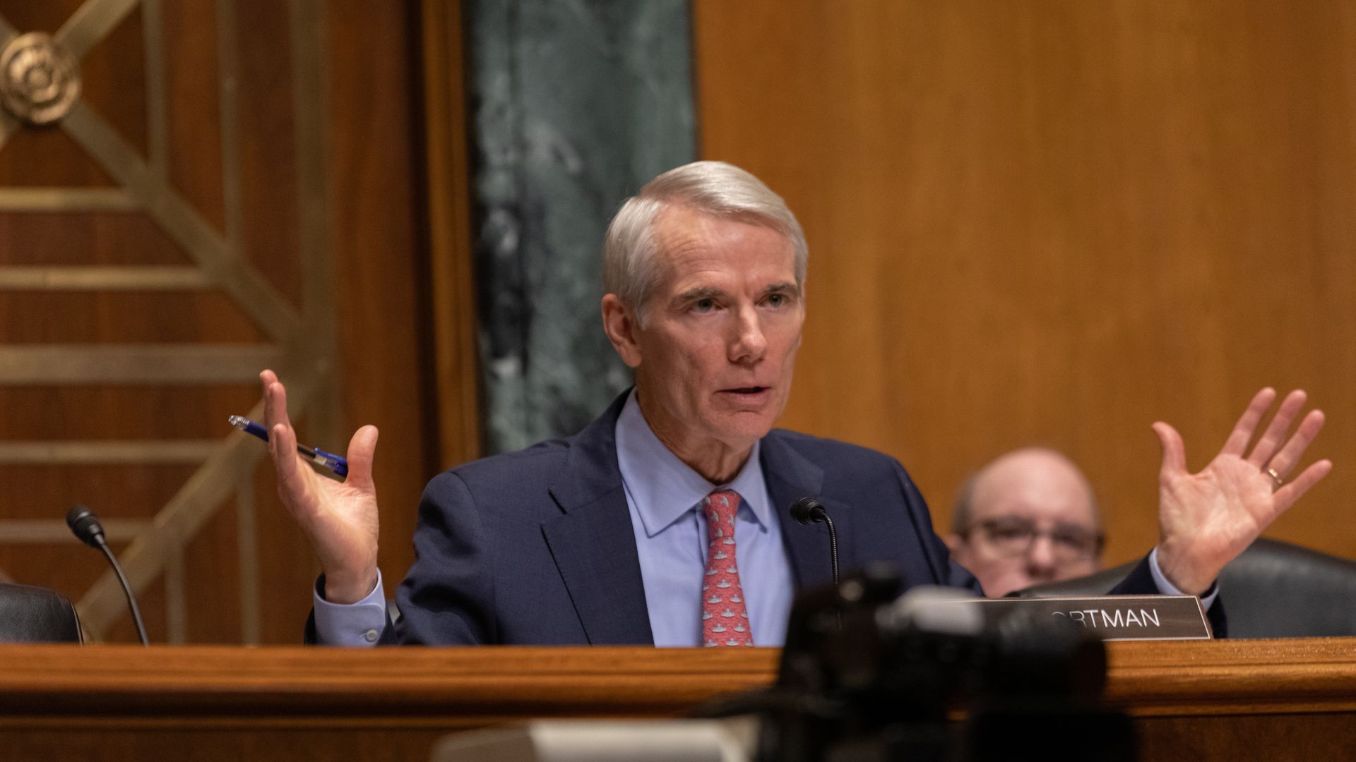 Rob Portman sits at a dais with his nameplate in front of it.