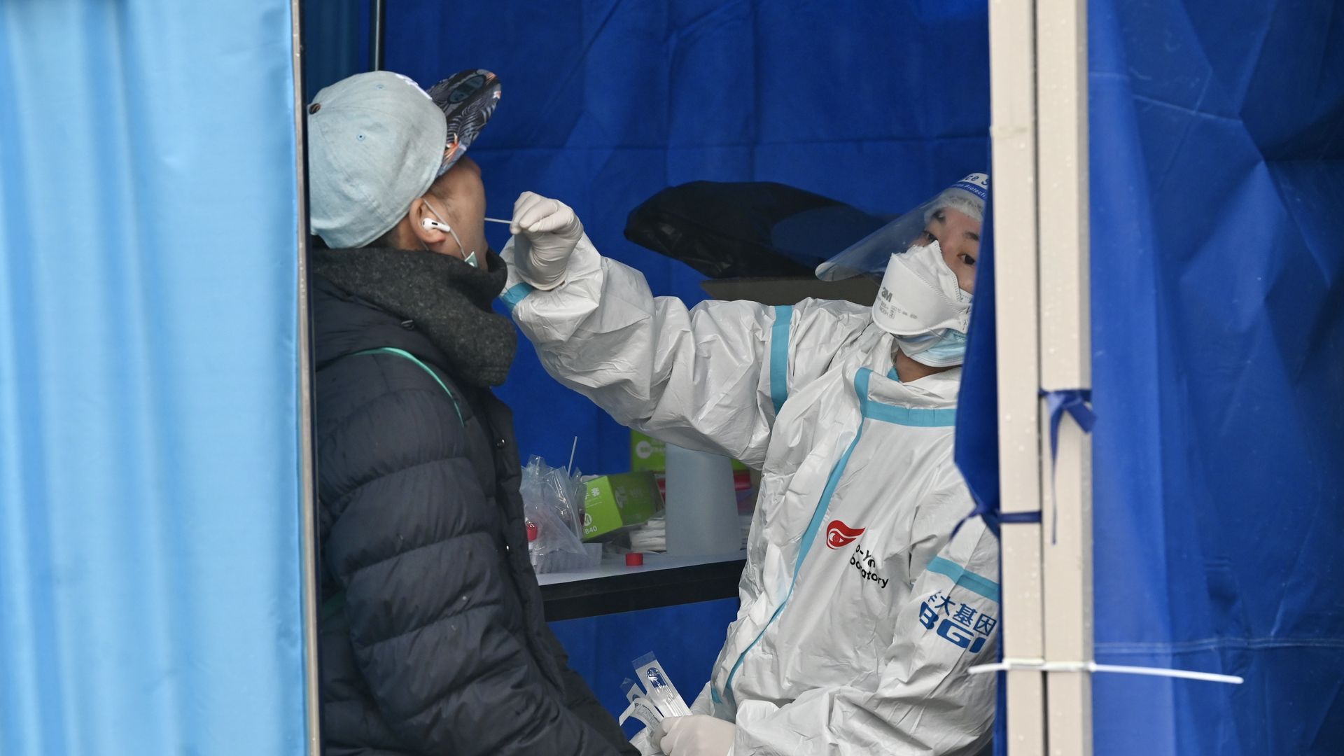 Picture of a person getting tested for COVID-19. A health professional is taking a mouth swab from the person.