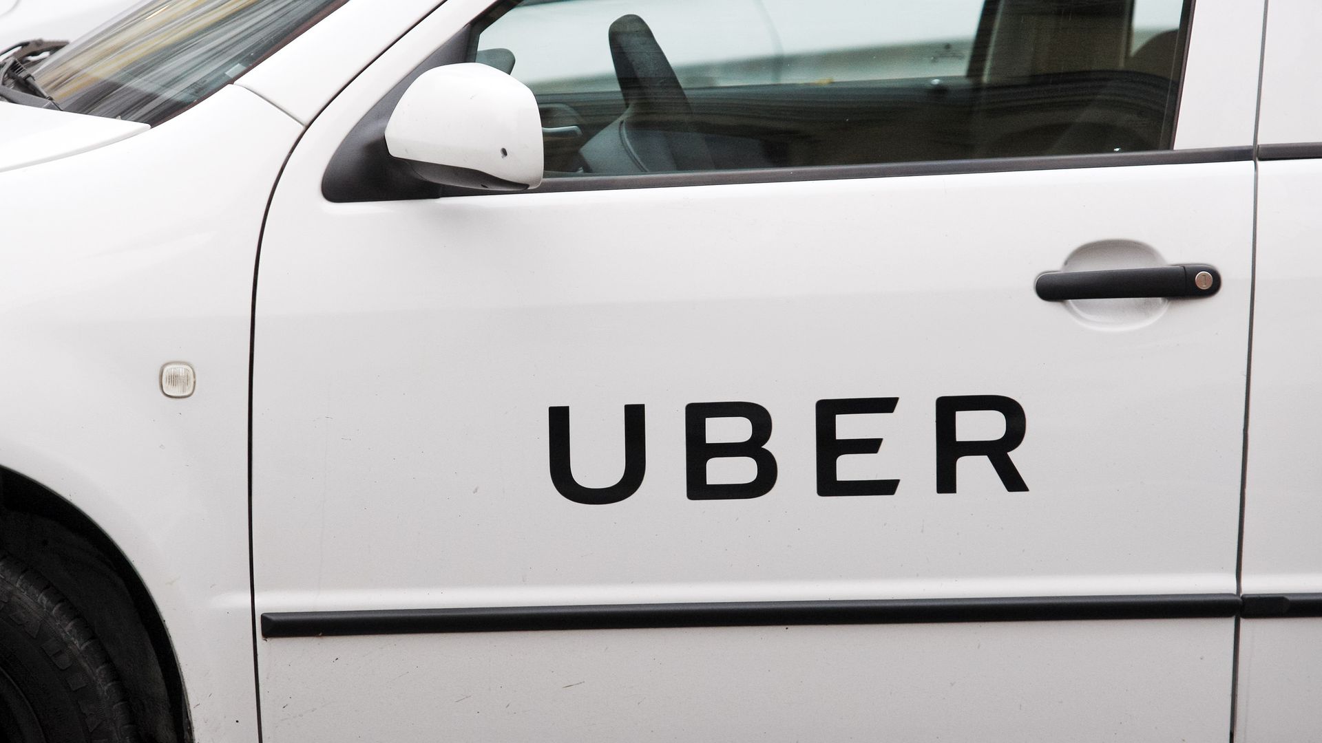 Uber logo on side of white car.