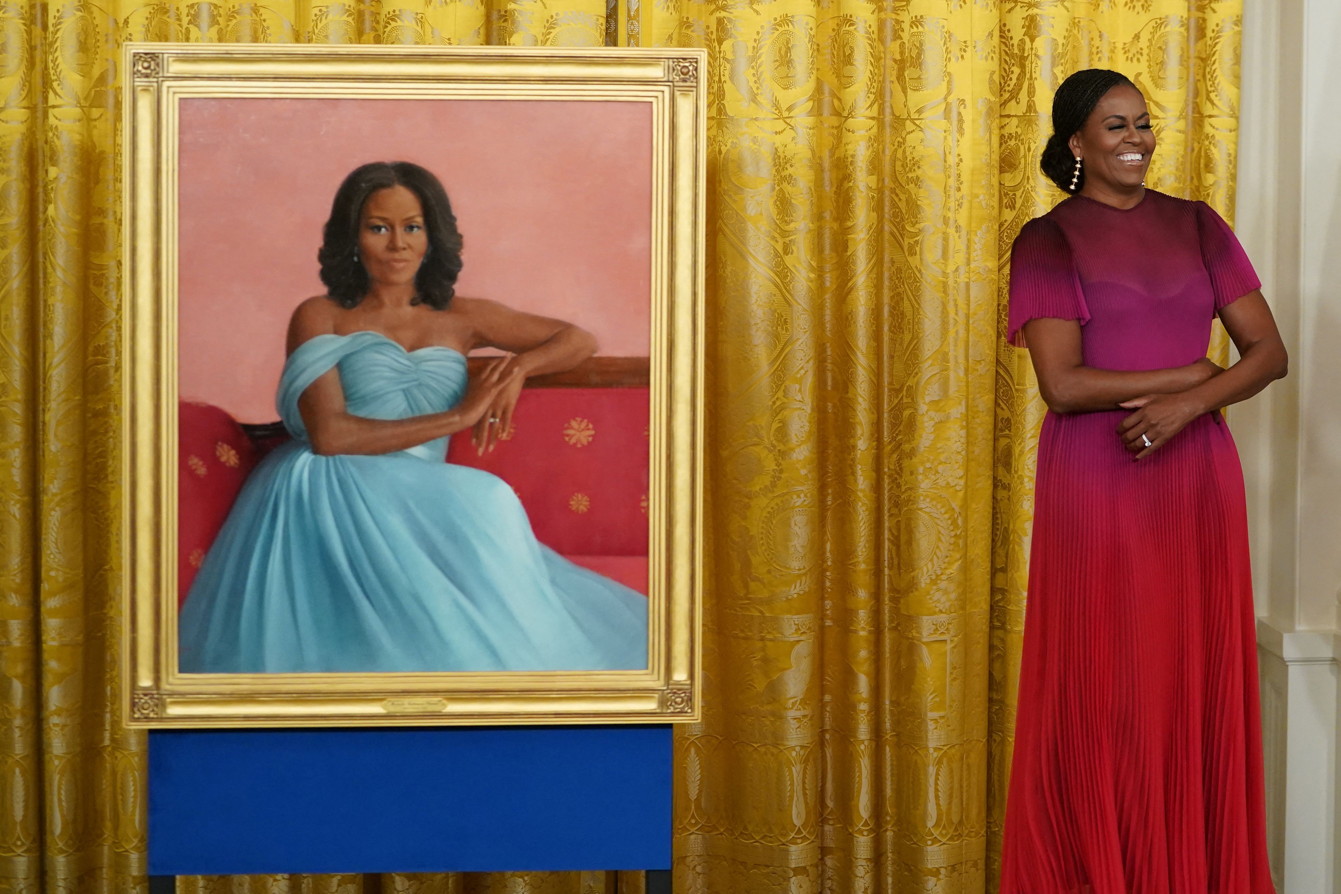 Former US First Lady Michelle Obama stands next to her newly unveiled official White House portrait.